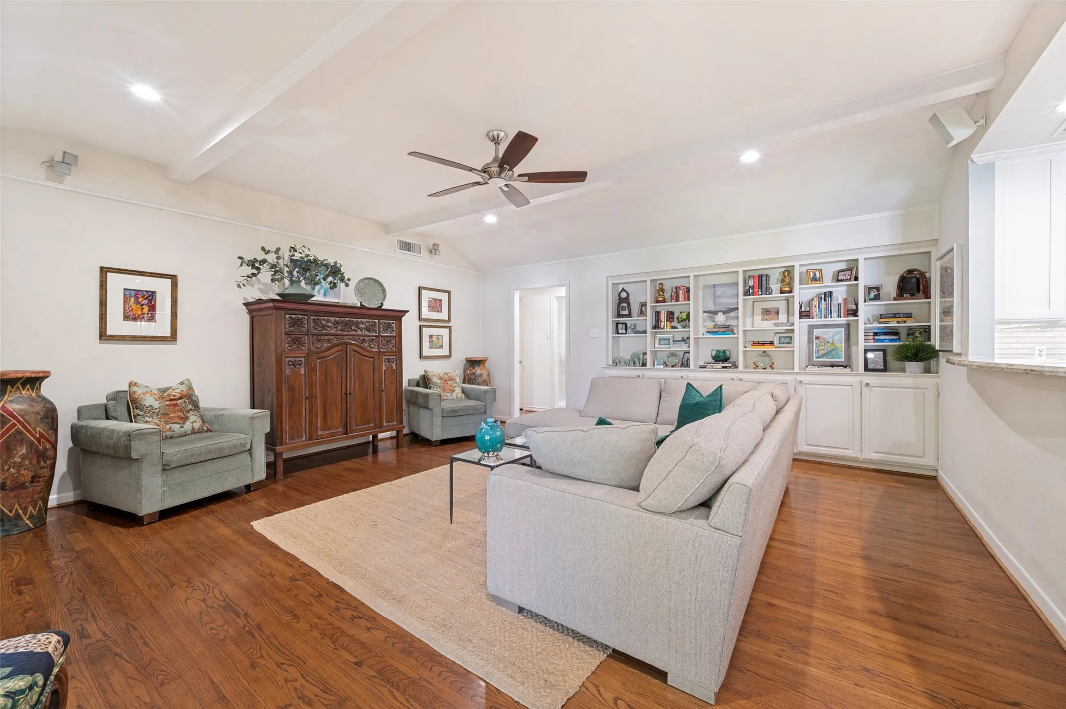 Hardwood flooring, vaulted ceiling, recessed lighting, ceiling fan, and built-in shelving with cabinetry