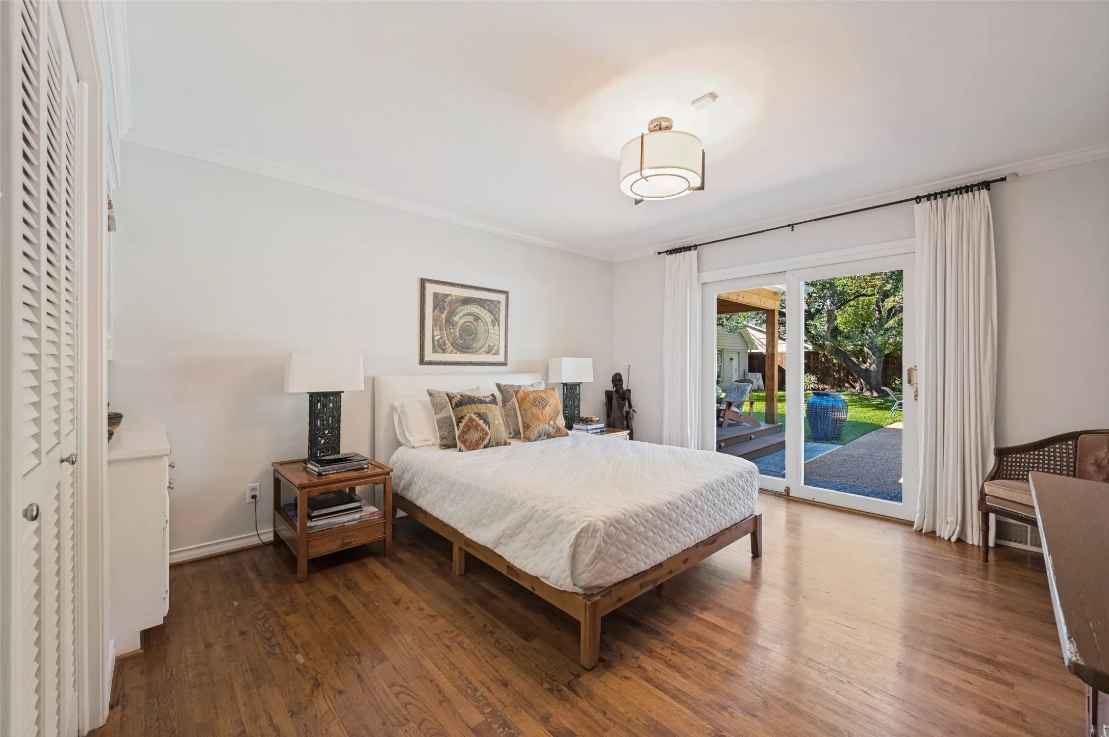 Hardwood flooring, crown molding, built-in louvered closet, ceiling-mounted light fixture, and sliding glass door leading to the pool area.