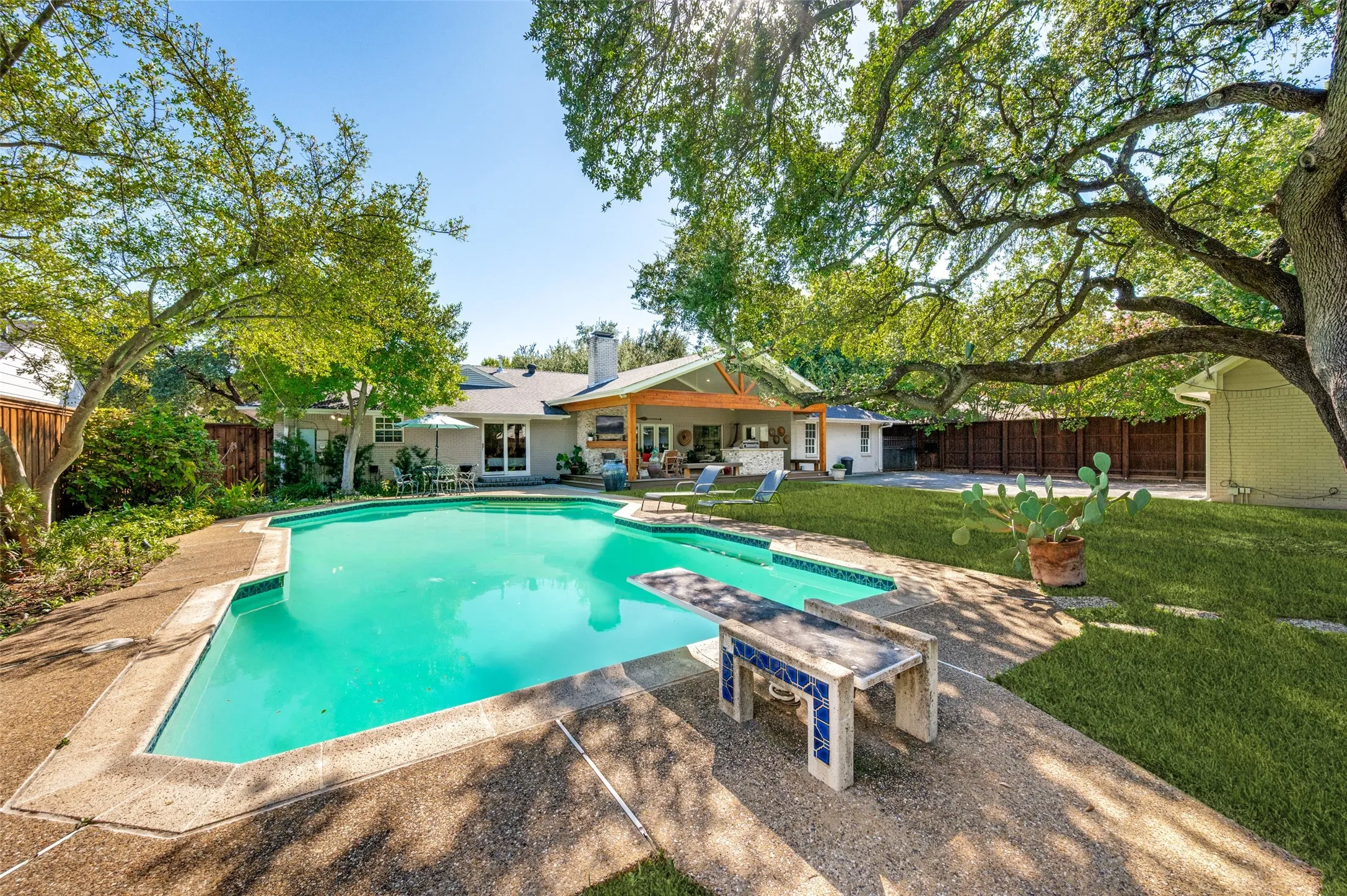 Expansive backyard with a large swimming pool, diving board, and concrete decking