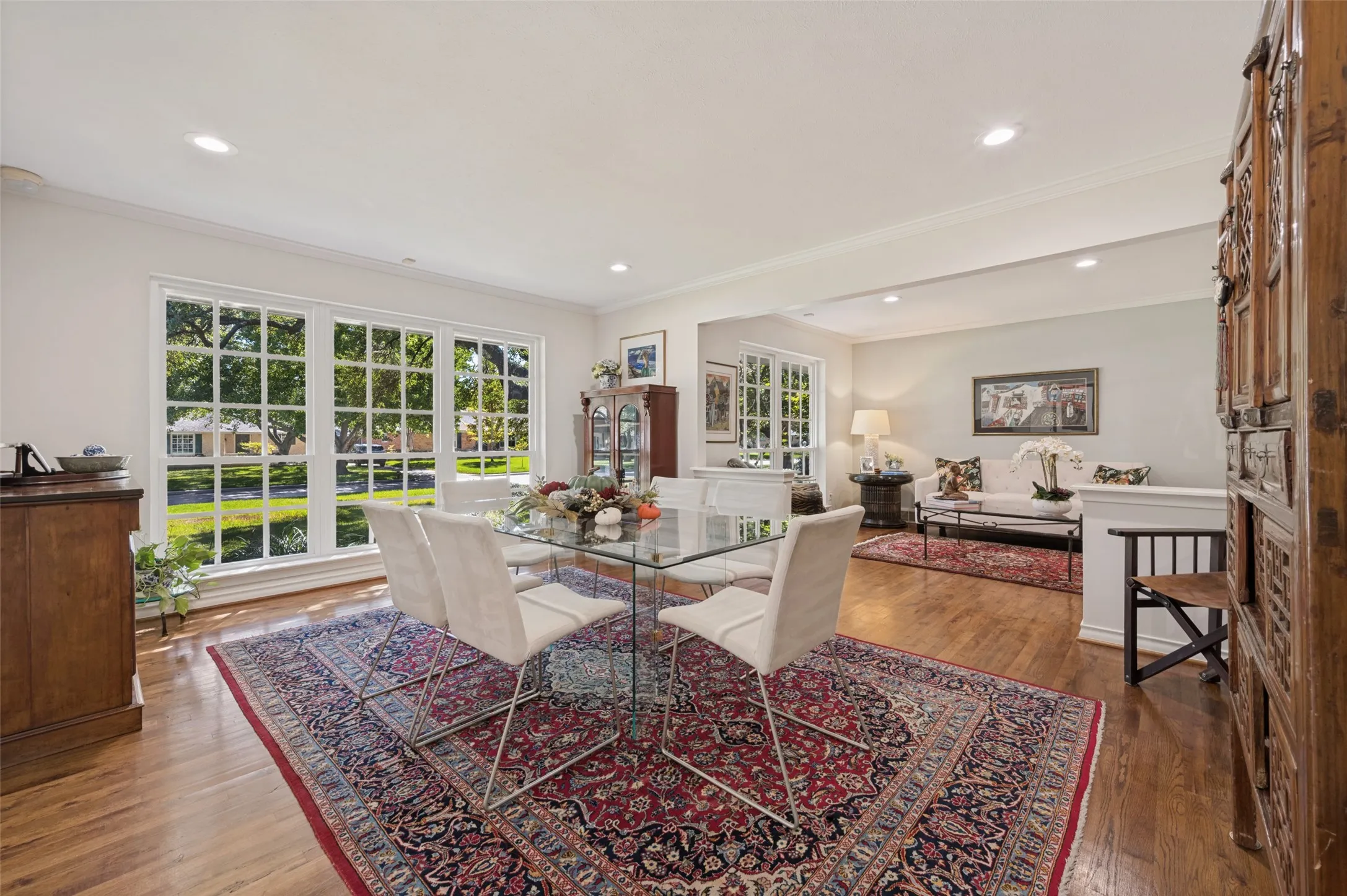 Hardwood flooring throughout, recessed lighting, white crown molding, large multi-pane windows, and a half-wall partition