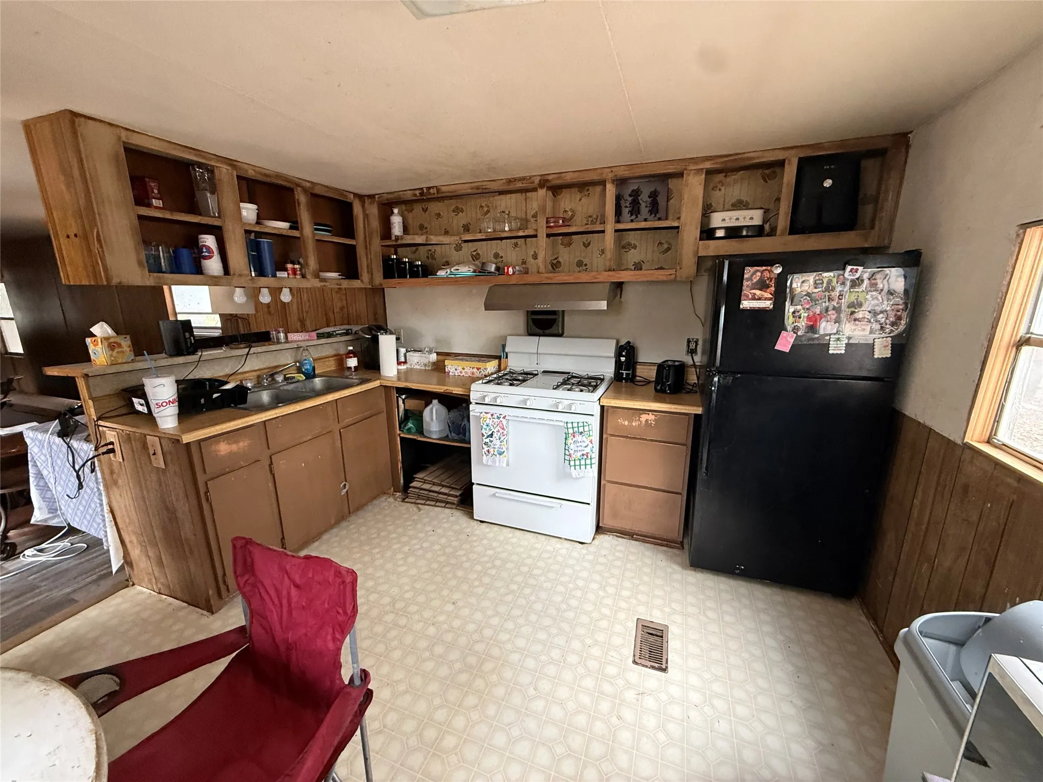 Built-in wood-finish cabinetry, white gas range, and a black refrigerator
