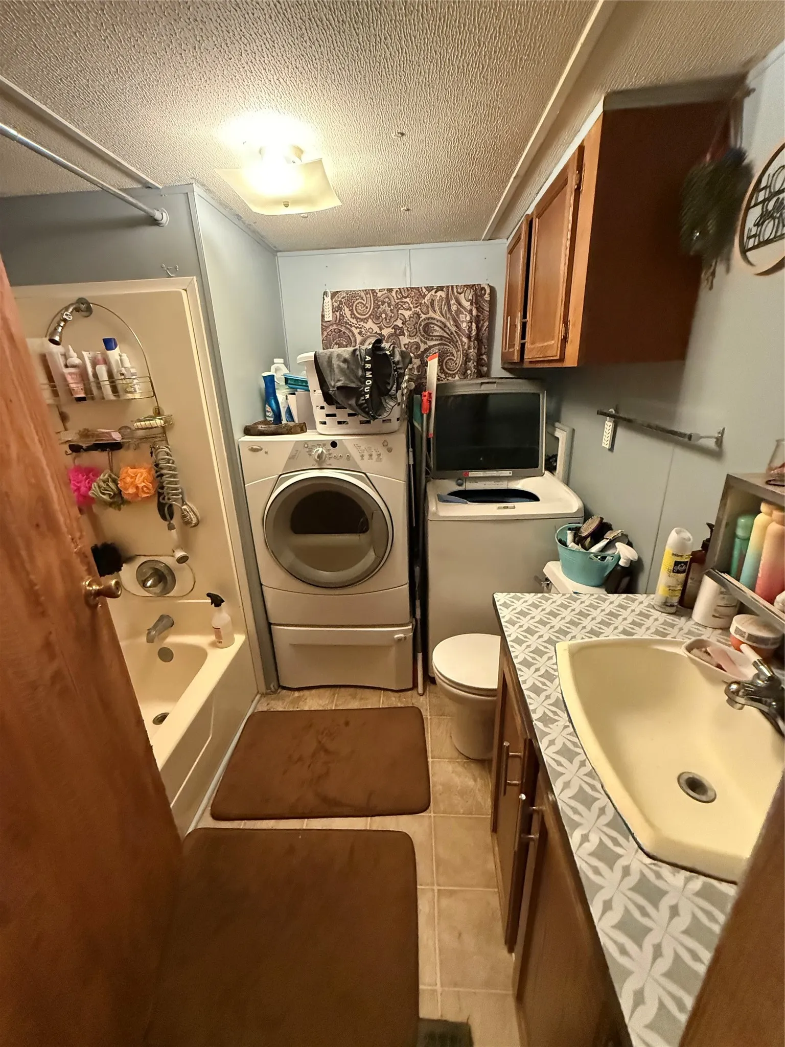 Bathroom featuring a full-size bathtub with shower, integrated vanity with sink, and overhead cabinetry