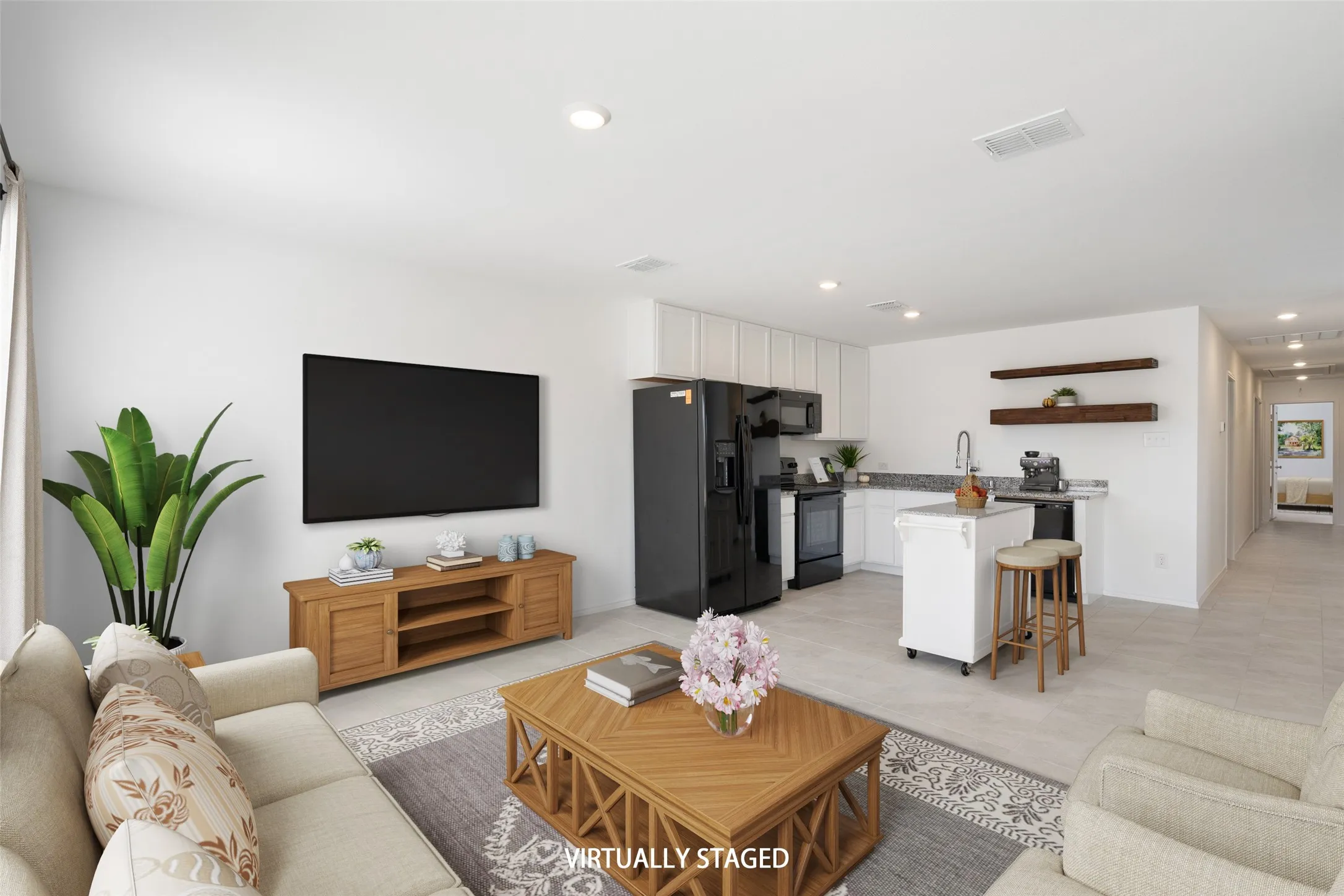 Open-concept living space featuring a kitchen with black appliances, white cabinetry, and a central island