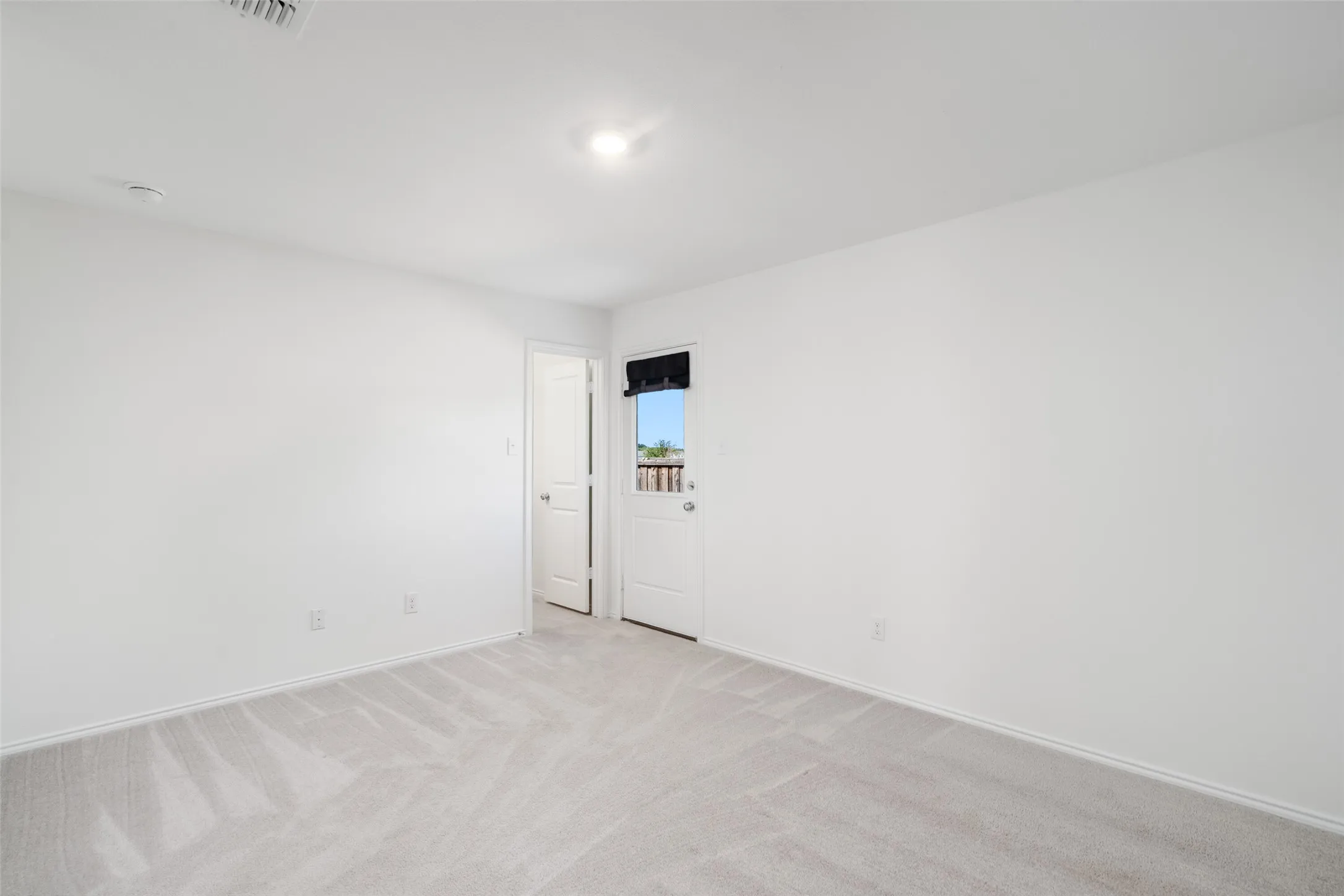 Recessed ceiling light, light-colored carpeting, white interior walls, white interior doors