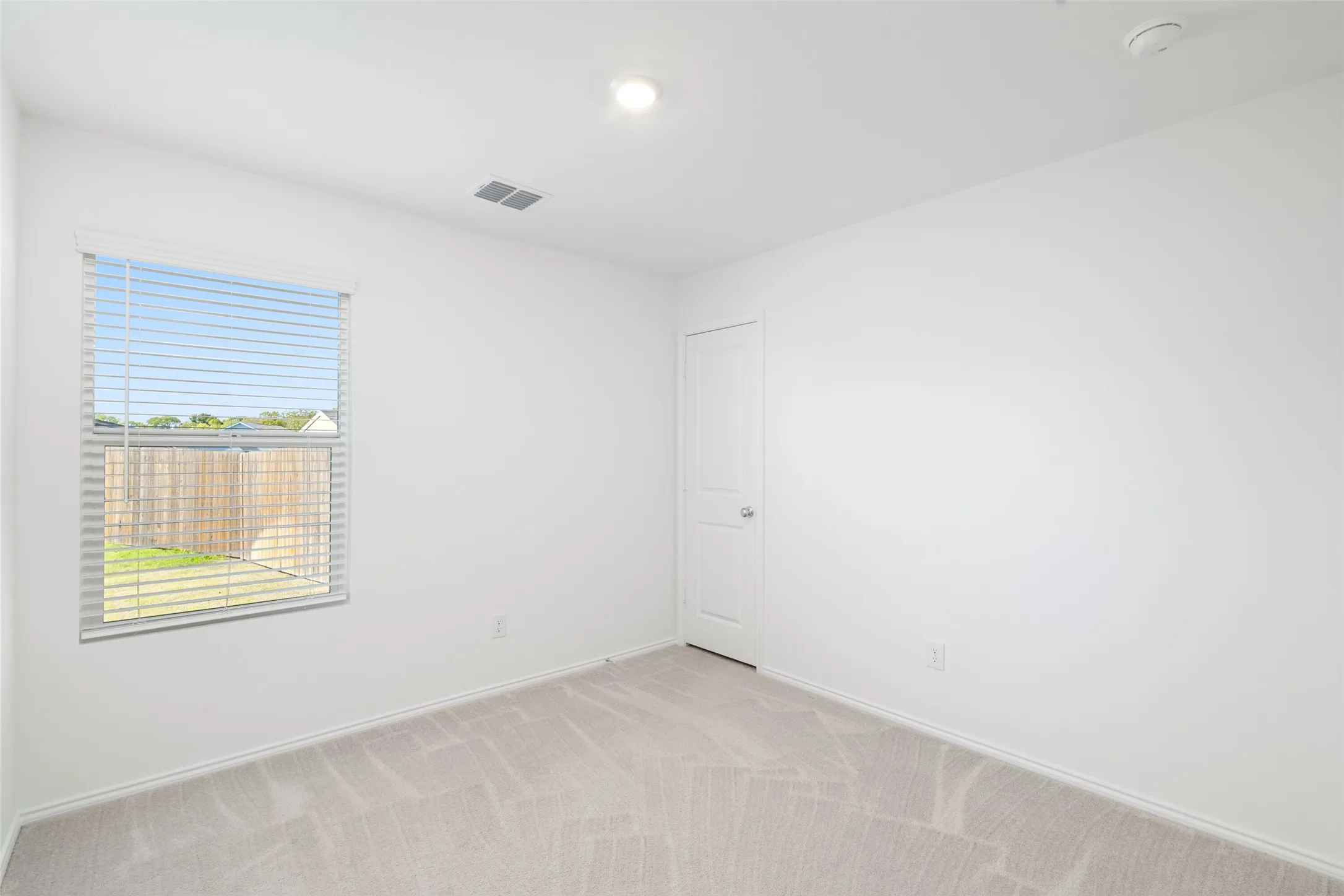 Neutral-toned carpeting, white painted walls, window with blinds, and recessed ceiling light