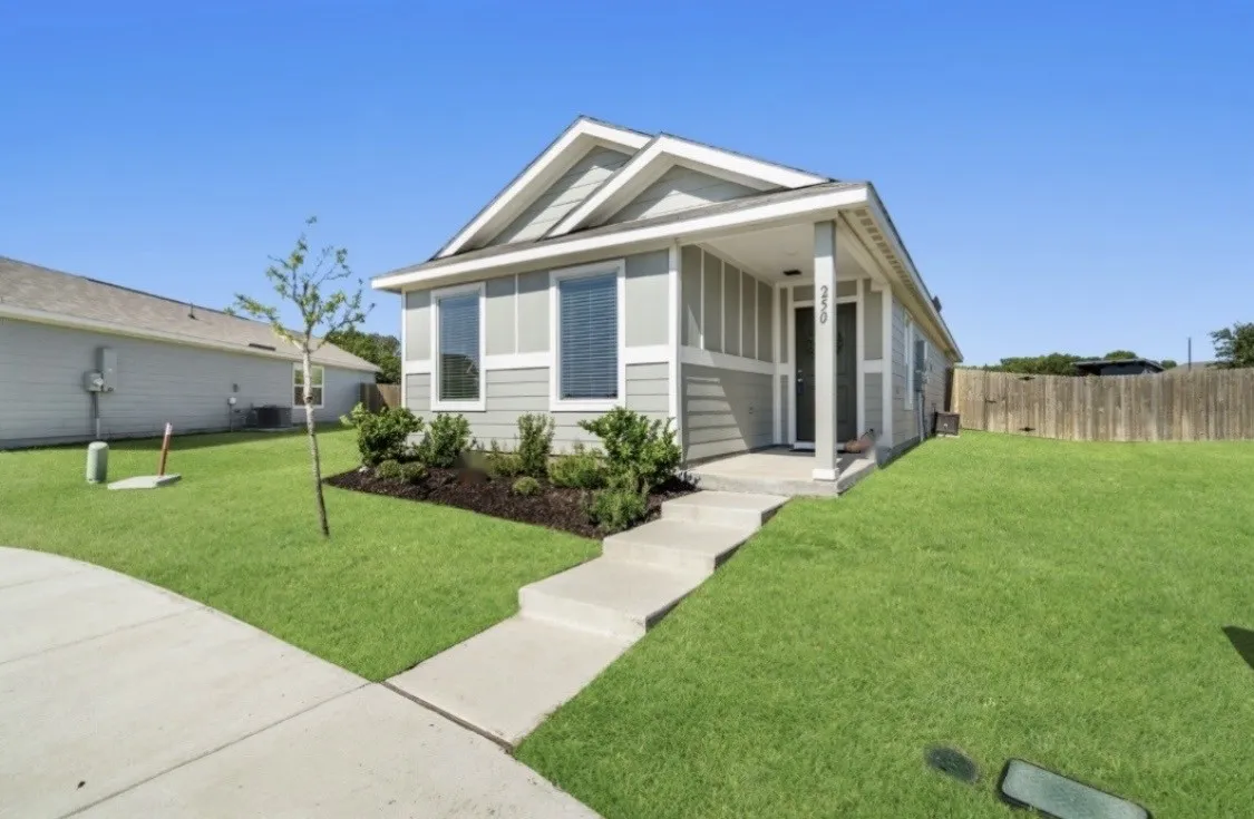 Single-story residence featuring light gray siding, white trim, a covered porch entry, and a concrete walkway