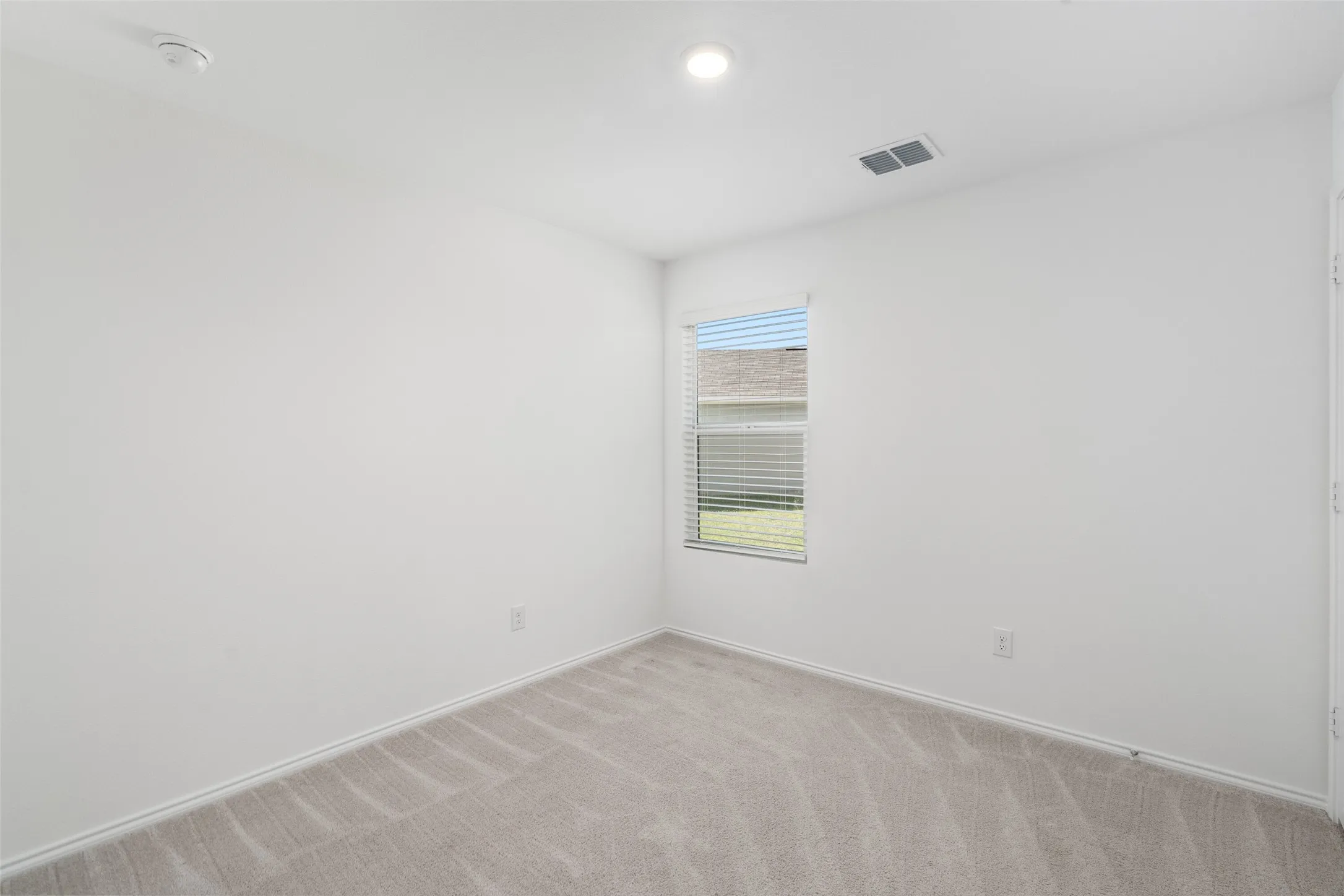 Carpeted flooring, recessed lighting, window with blinds, white walls, and a ceiling-mounted ventilation register