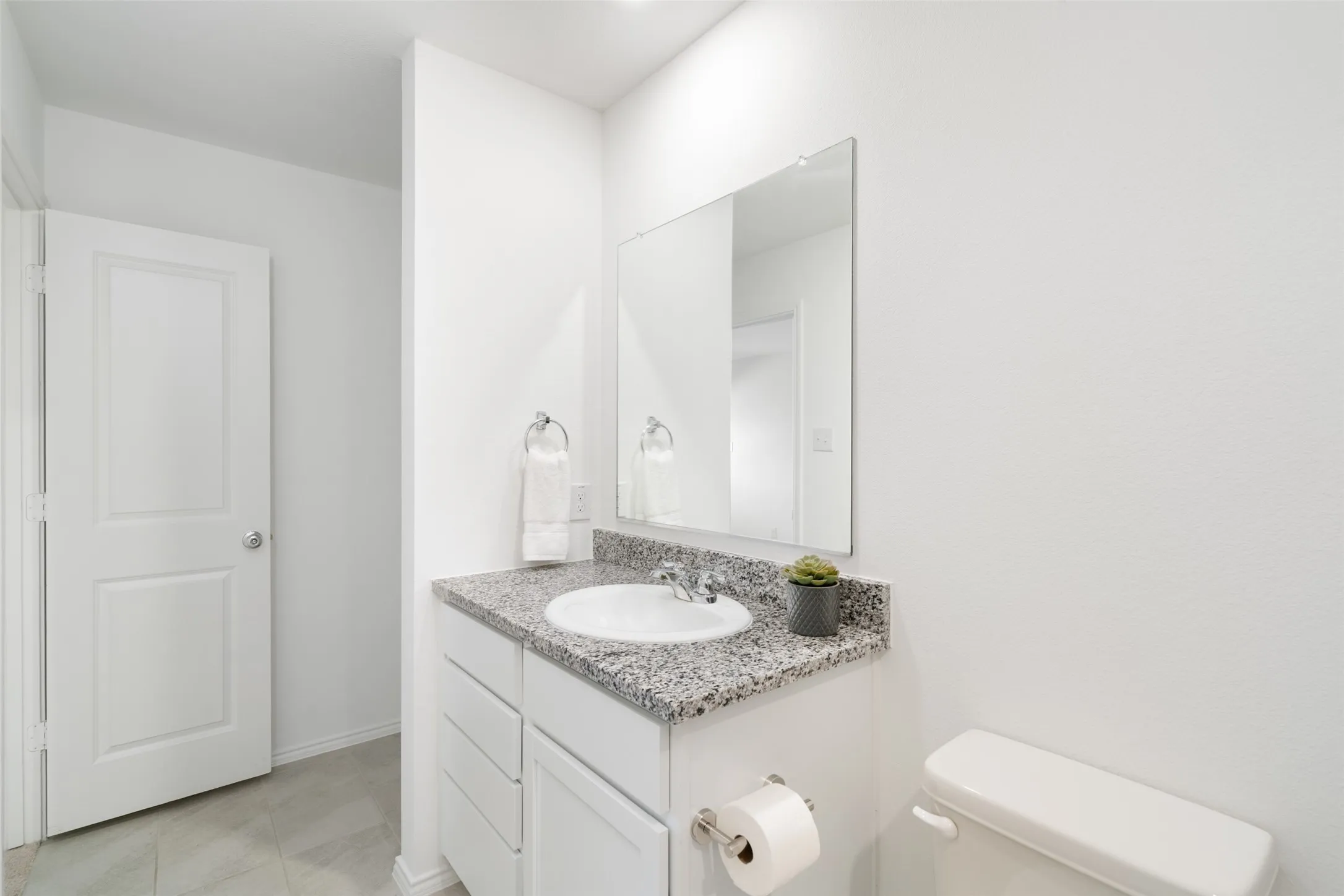 White vanity with a granite countertop, integrated sink, and chrome faucet