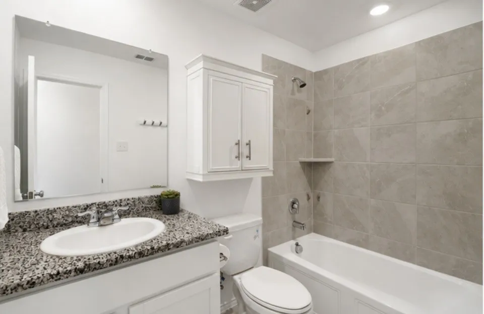 Bathroom featuring a single vanity with stone-finish countertop, undermount sink, and polished chrome faucet