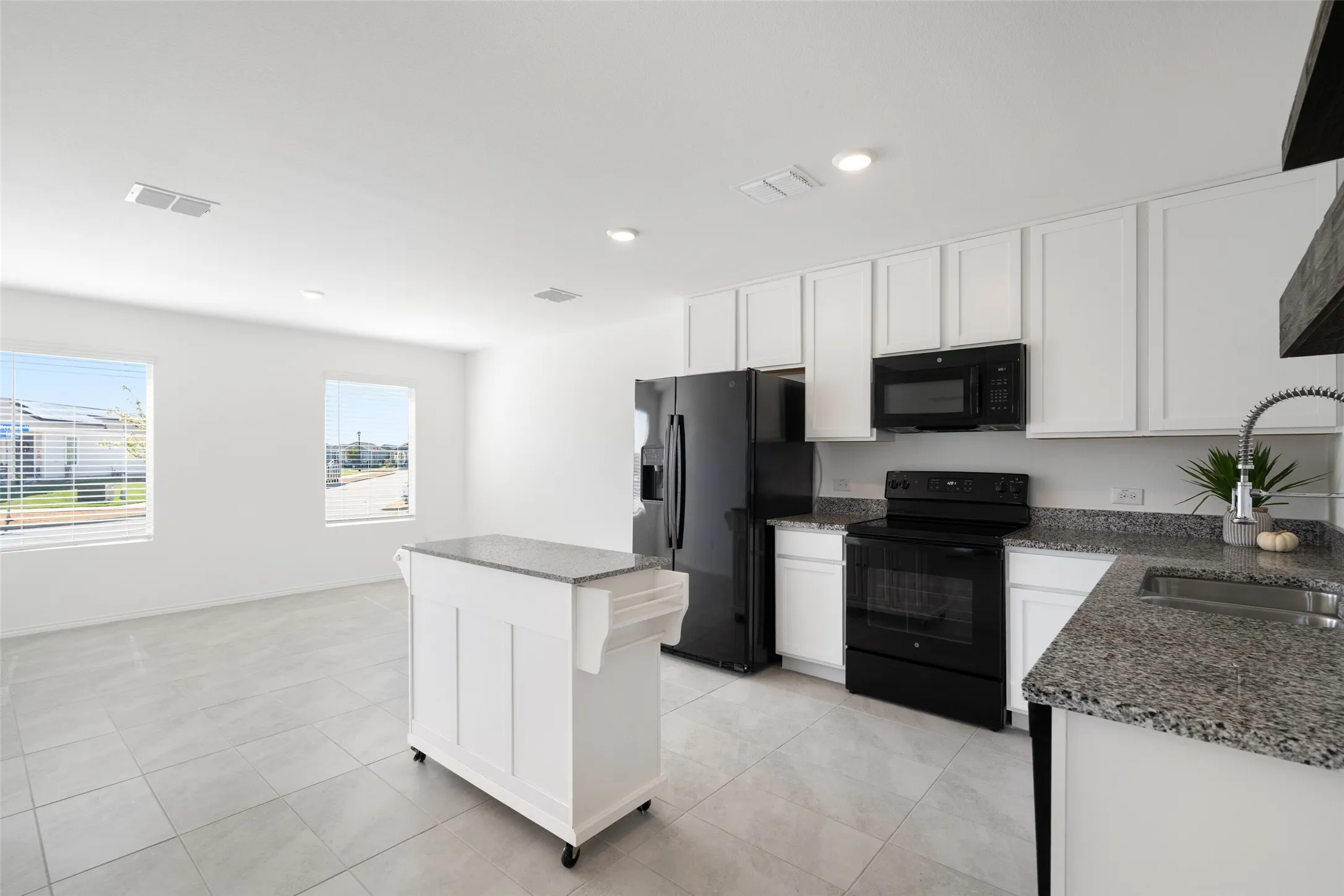 Kitchen featuring white cabinetry, granite countertops, black appliances, a stainless steel sink with a pull-down faucet, and tile flooring