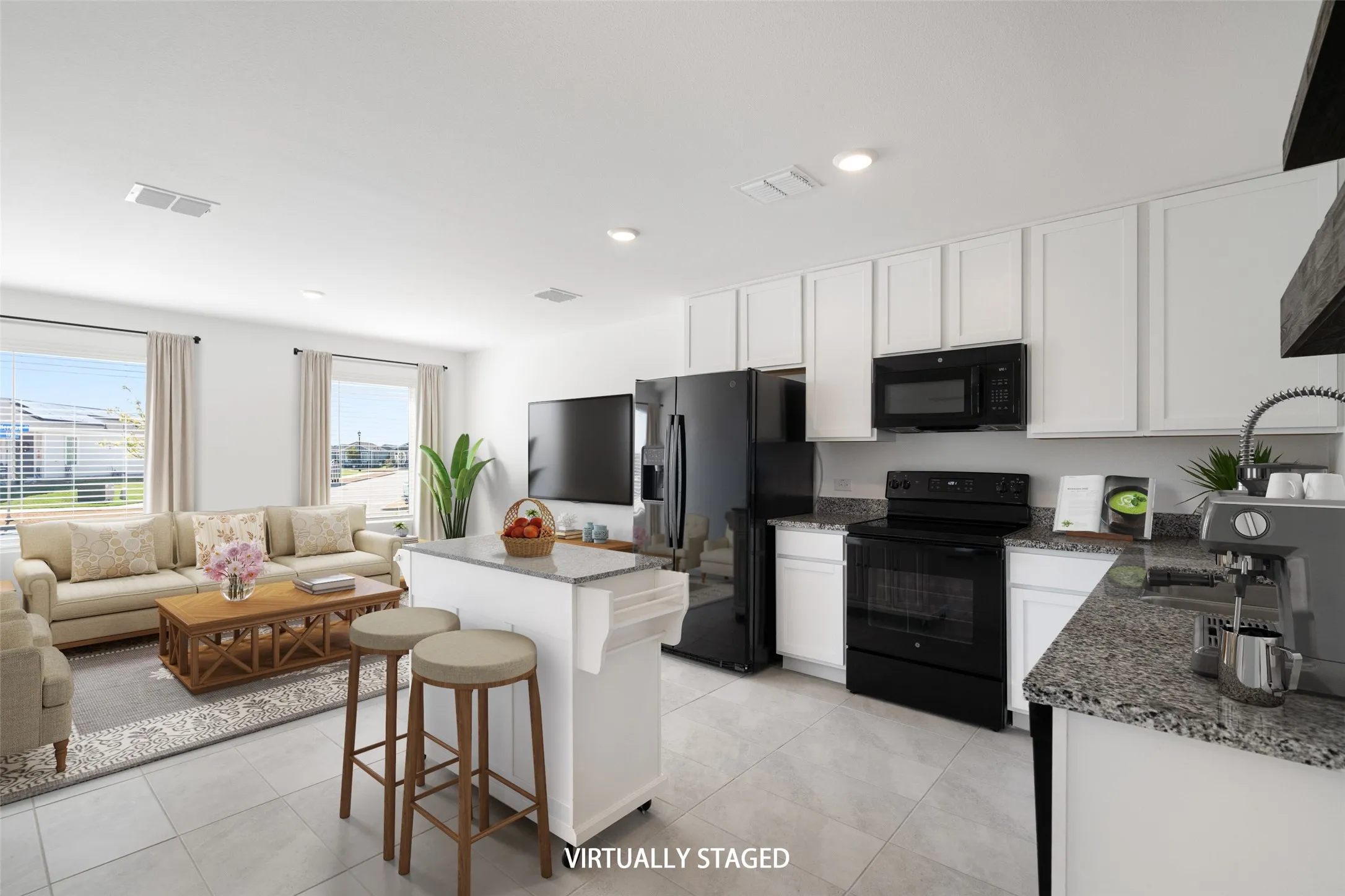 Open concept living space featuring a kitchen island with seating, granite-finish countertops, black appliances, white shaker-style cabinetry, and tile flooring