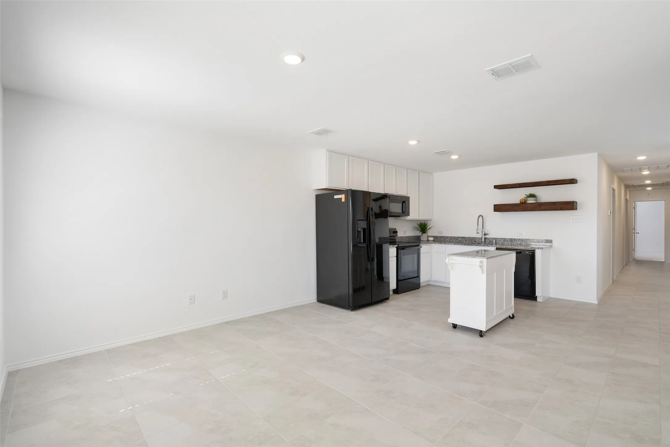 Open-concept living area with light-toned tile flooring and recessed lighting