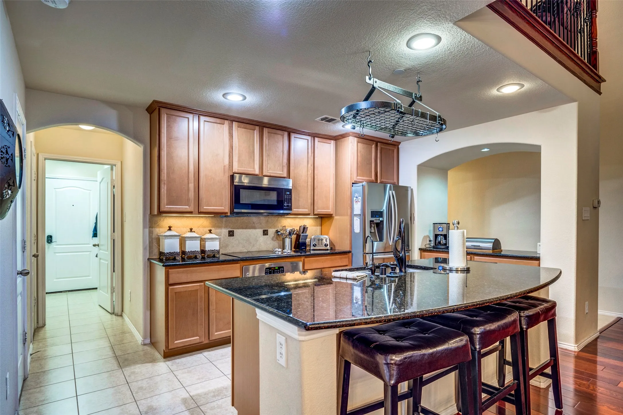 Kitchen featuring wood cabinetry, stainless steel appliances, recessed lighting, and an expansive island with a dark countertop