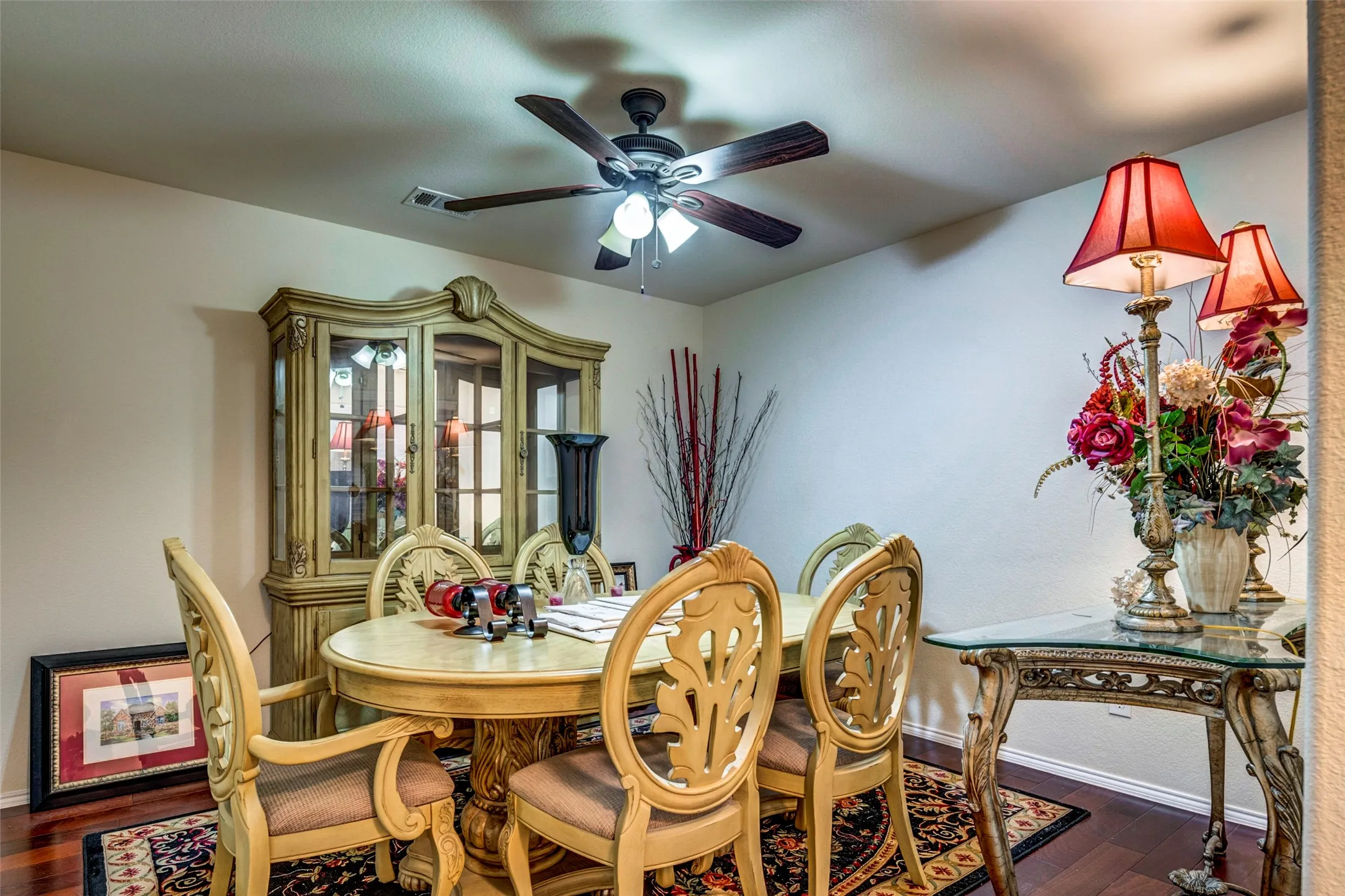 Wood-finish flooring, ceiling fan, built-in display cabinet with glass panels, and wall-mounted light fixtures