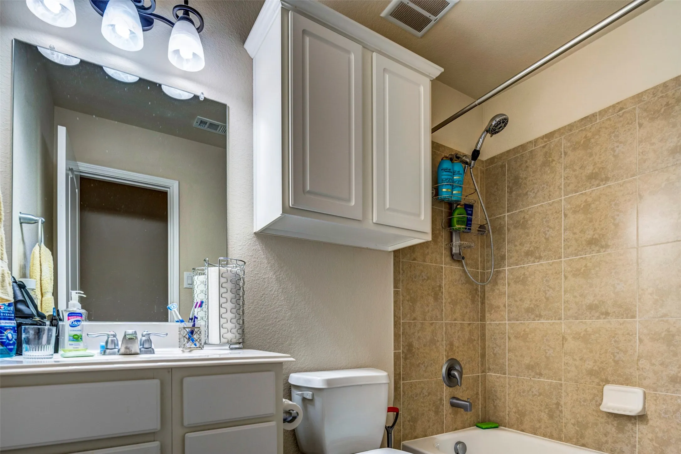 Bathroom featuring a vanity with white cabinetry, a rectangular mirror, and a three-light fixture