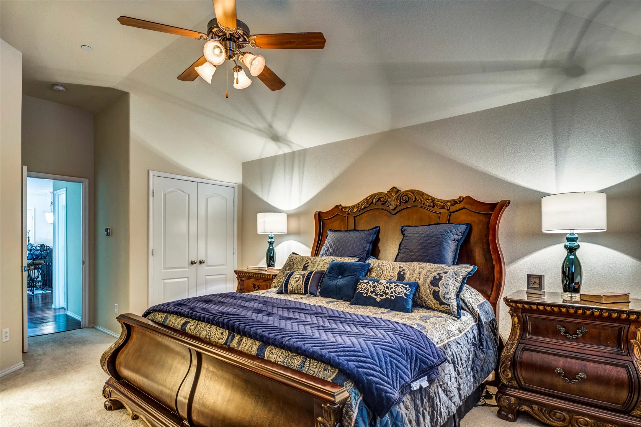 Vaulted ceilings with a ceiling fan, carpet flooring, and double-door closet