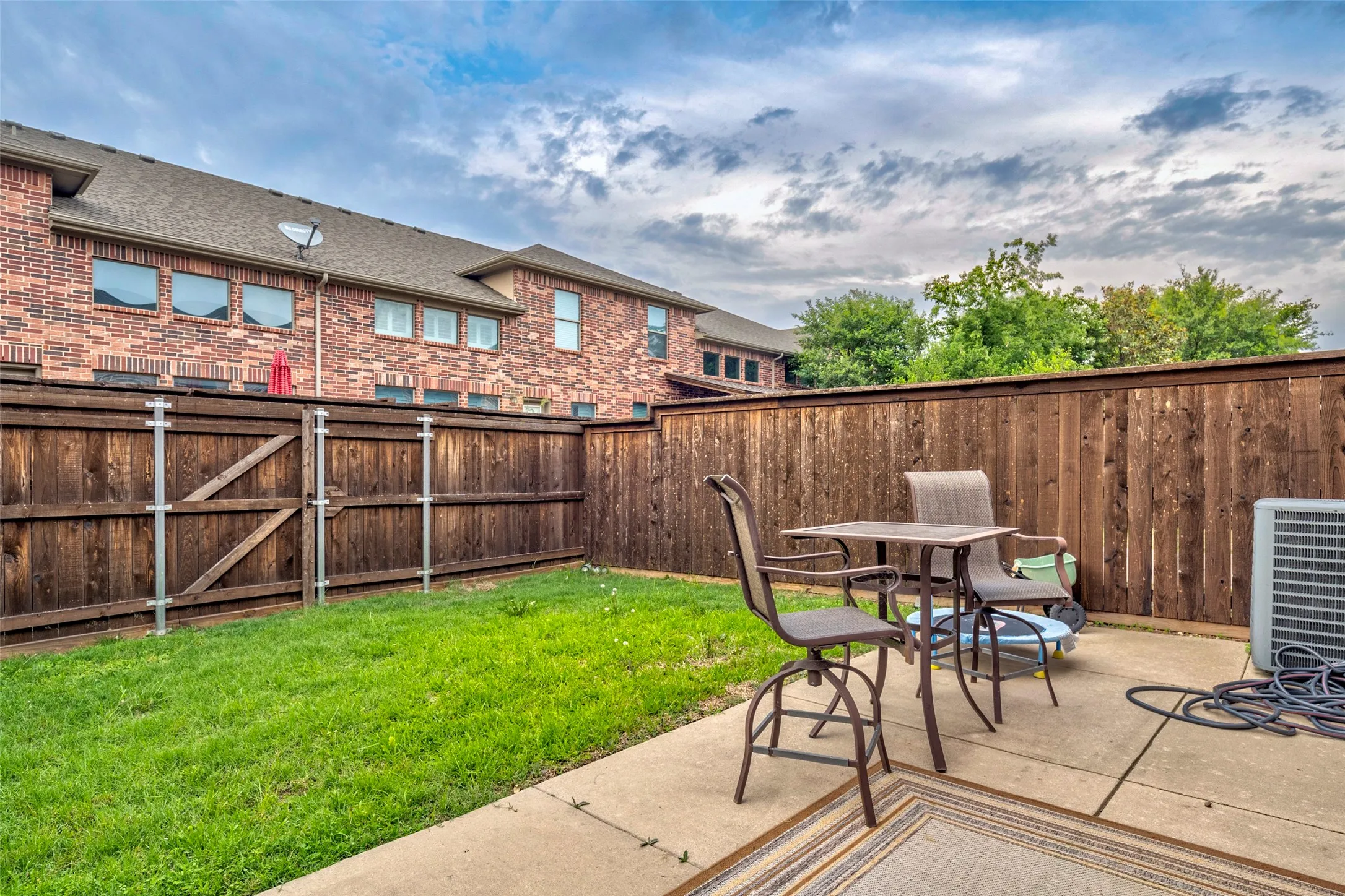 Expansive wood privacy fencing surrounds a green lawn and concrete patio