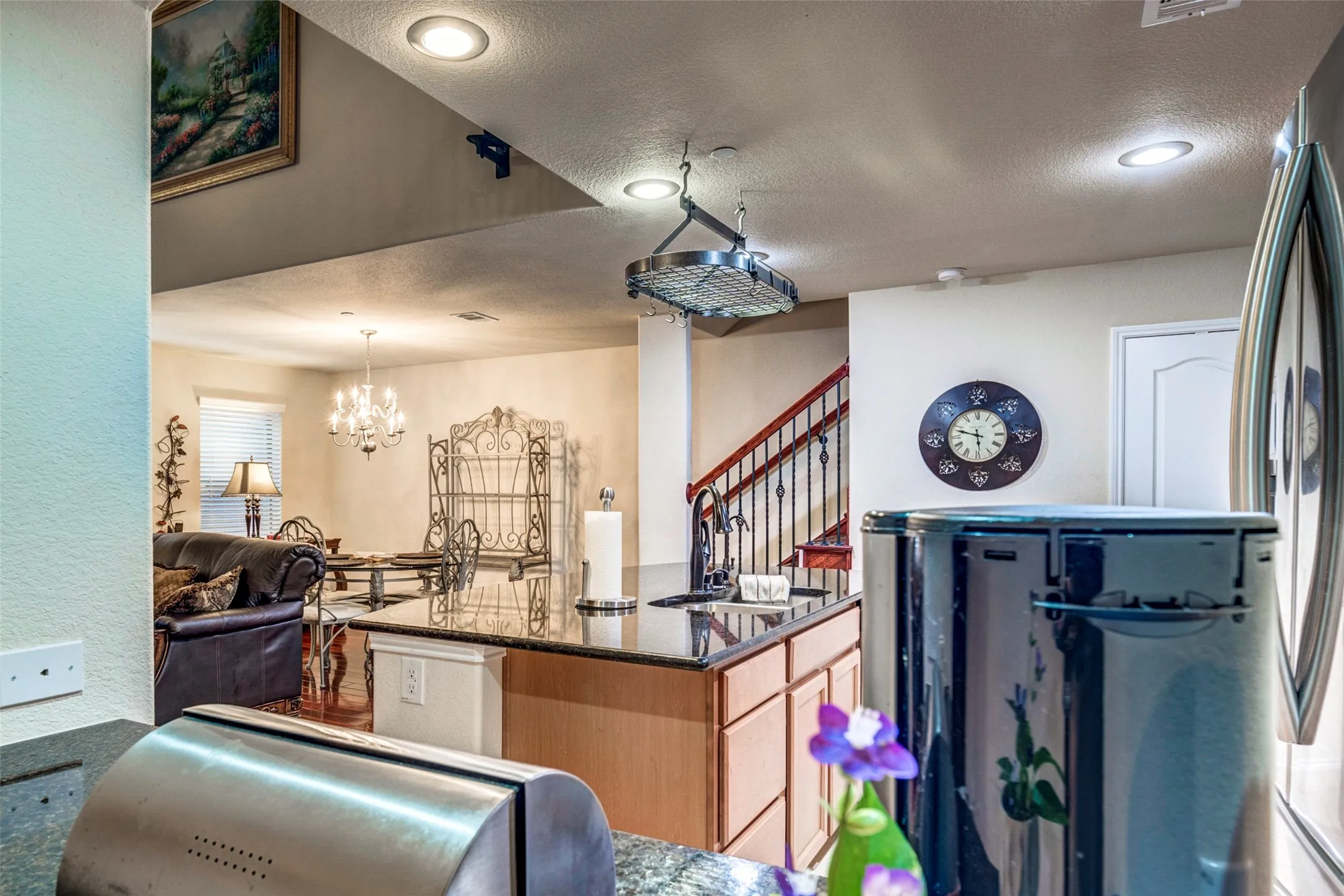 Kitchen island with granite-finish countertop, wood-finish cabinetry, and recessed lighting
