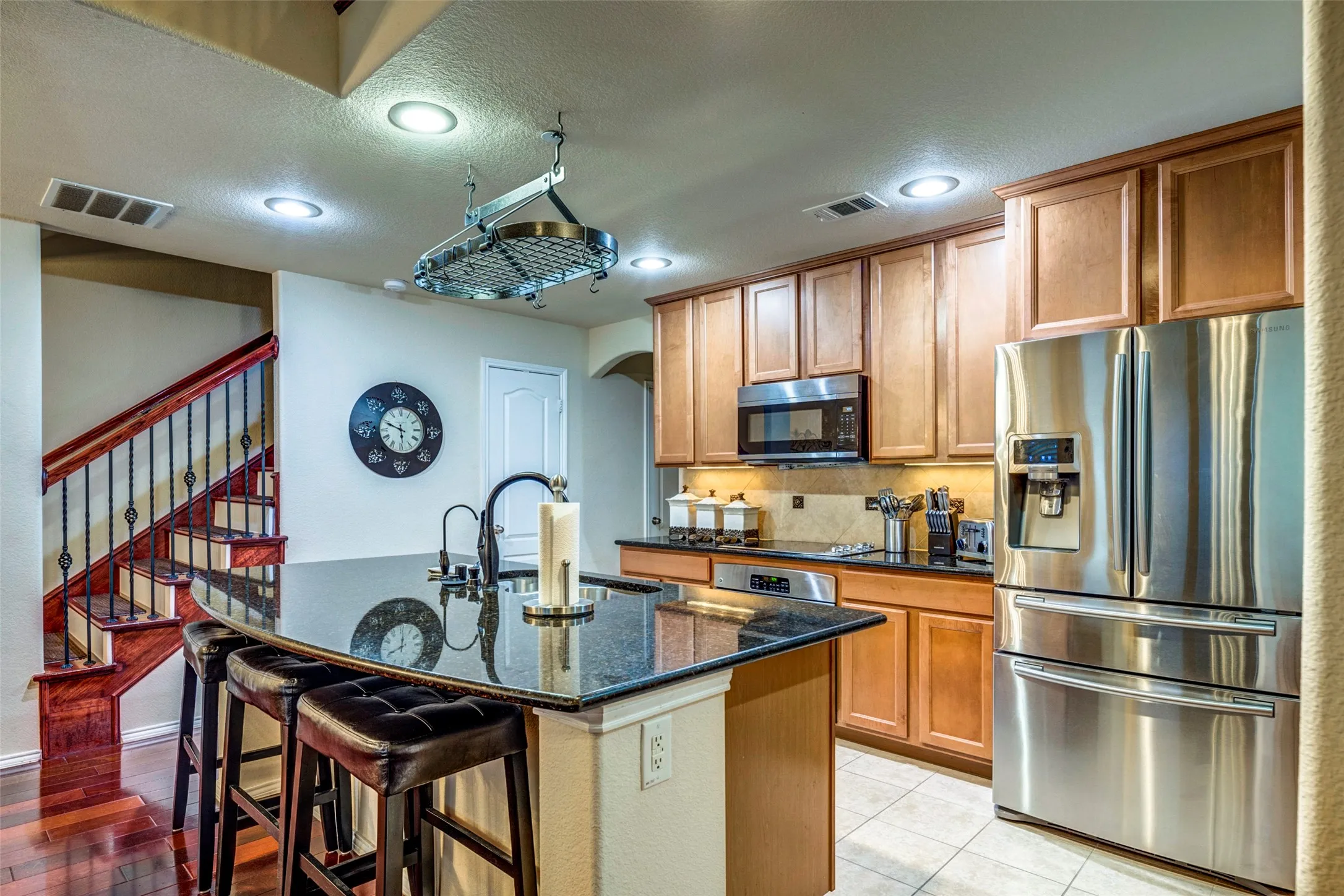 Gourmet kitchen with stainless steel appliances, granite countertops, wood cabinetry, and recessed lighting