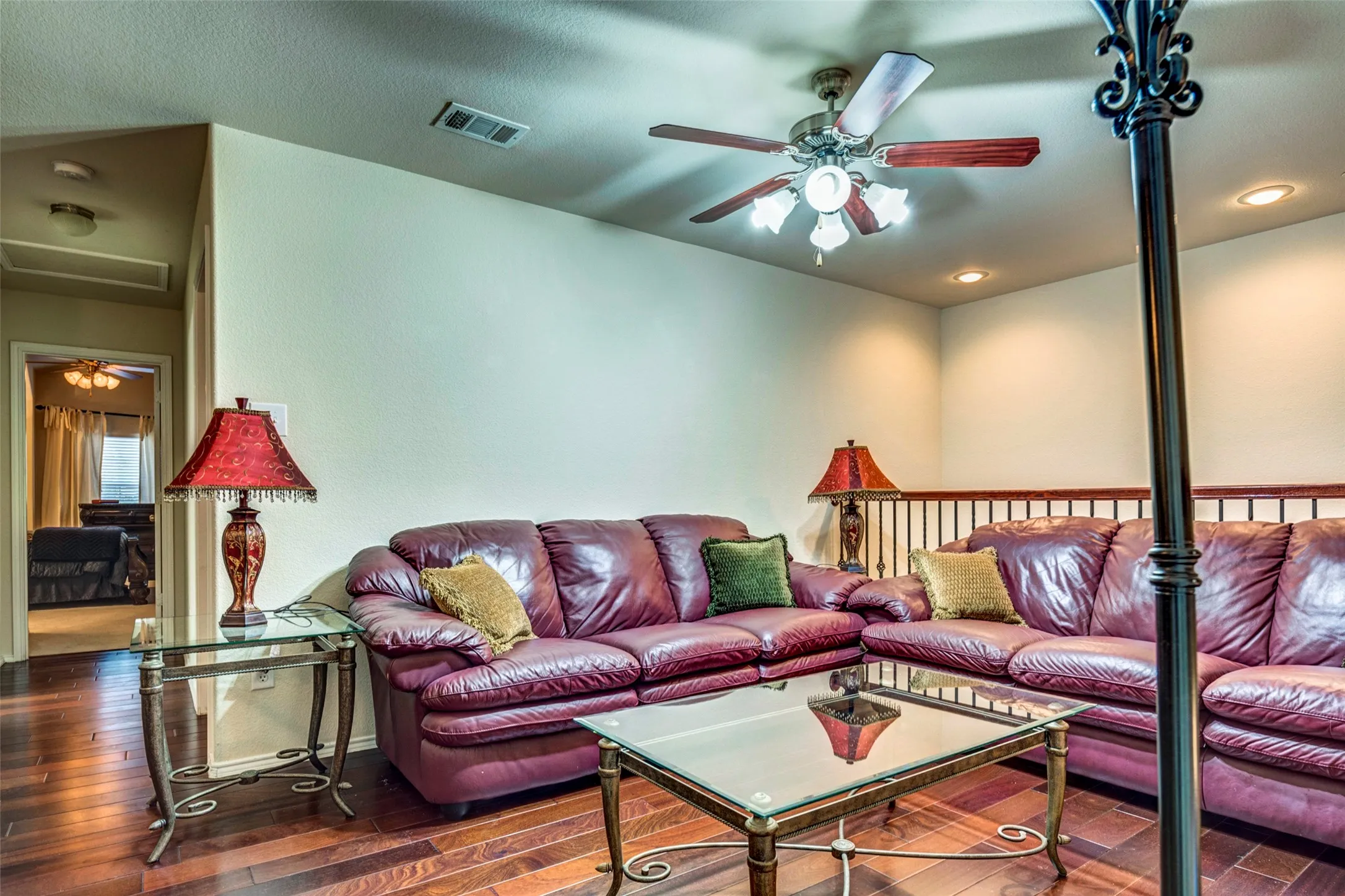 Recessed lighting, wood-finish flooring, ceiling fan with light fixture, and a metal spindle railing