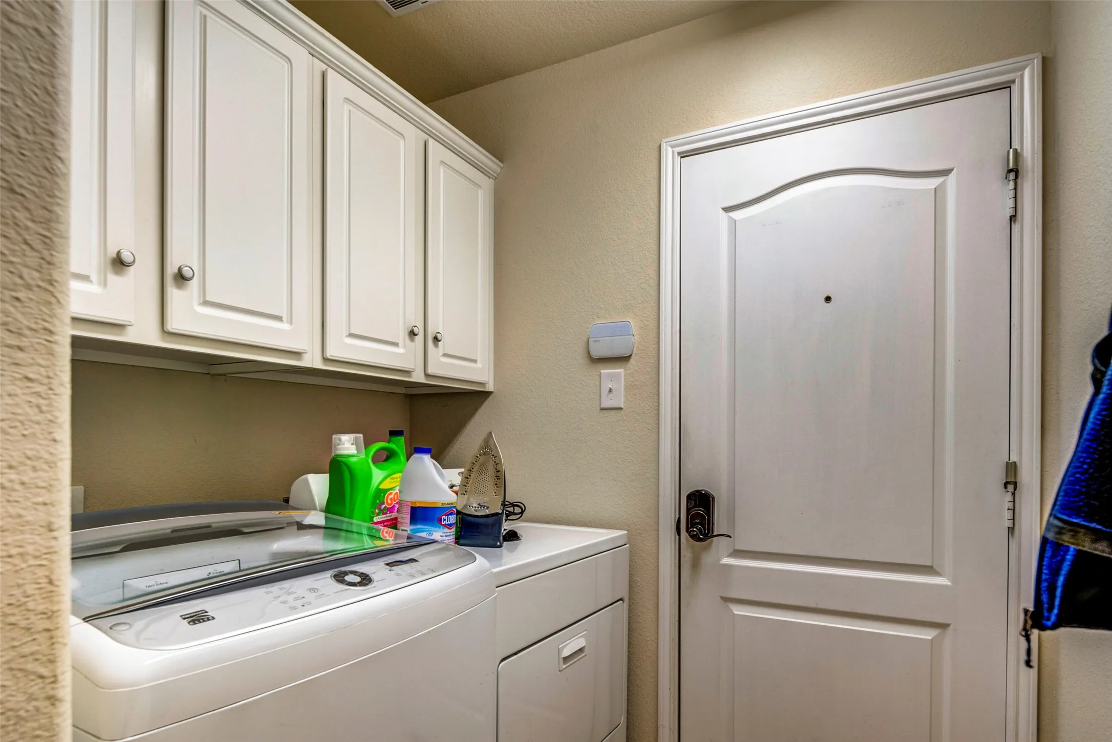 Built-in white cabinetry with chrome hardware, white paneled door with dark hardware, and a light wall color