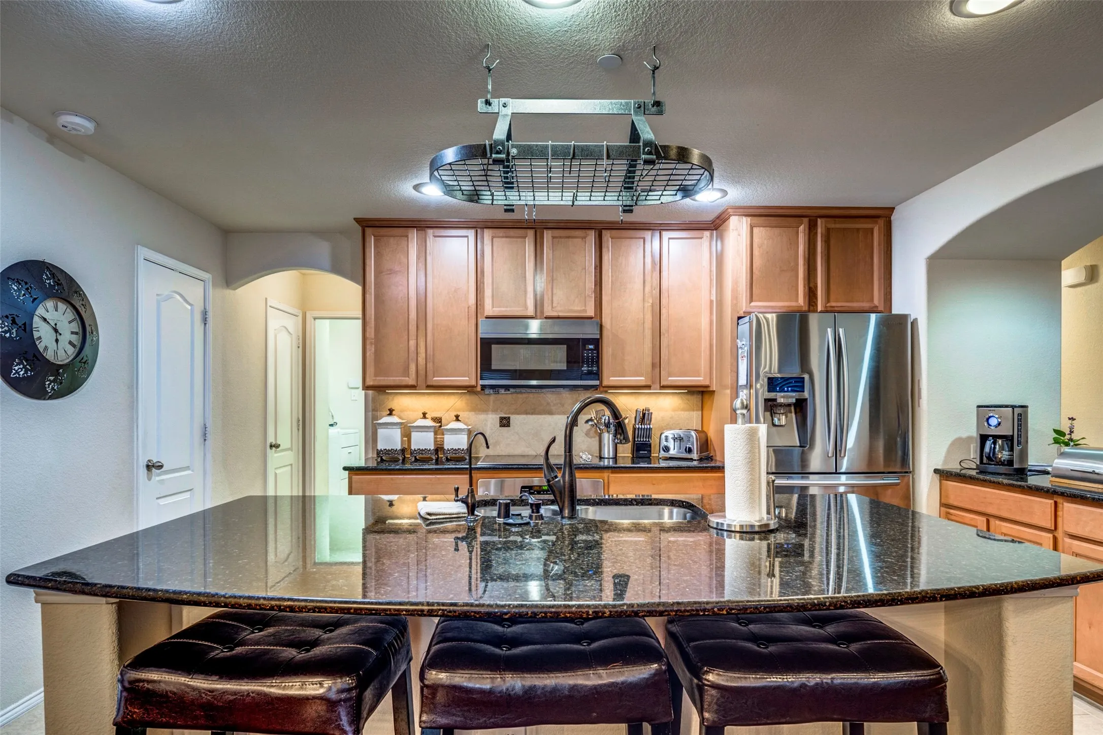 Kitchen featuring a large island with an undermount sink, granite countertops, wood cabinetry, and stainless steel appliances