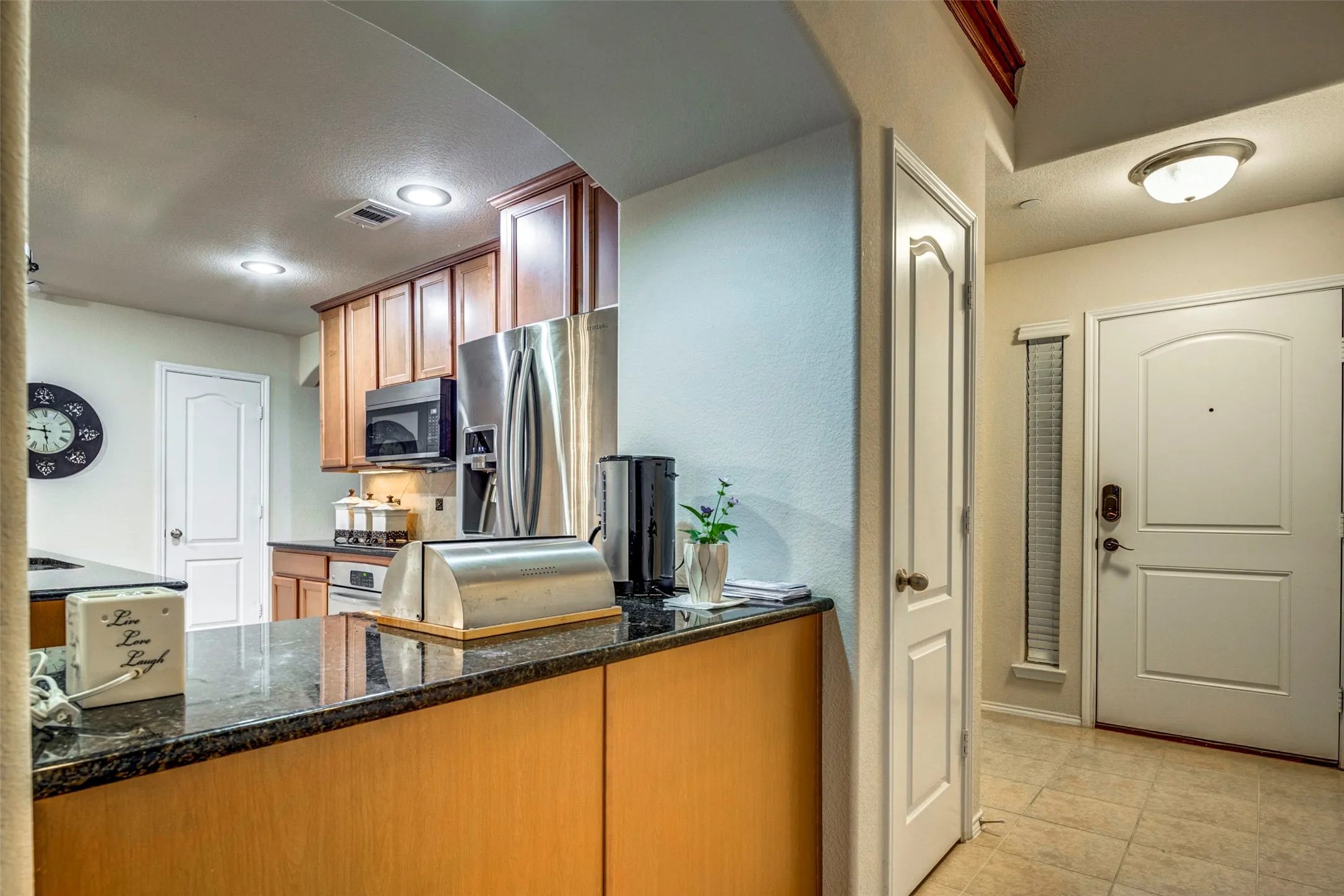 Kitchen featuring wood cabinetry, stainless steel appliances, and dark granite countertops