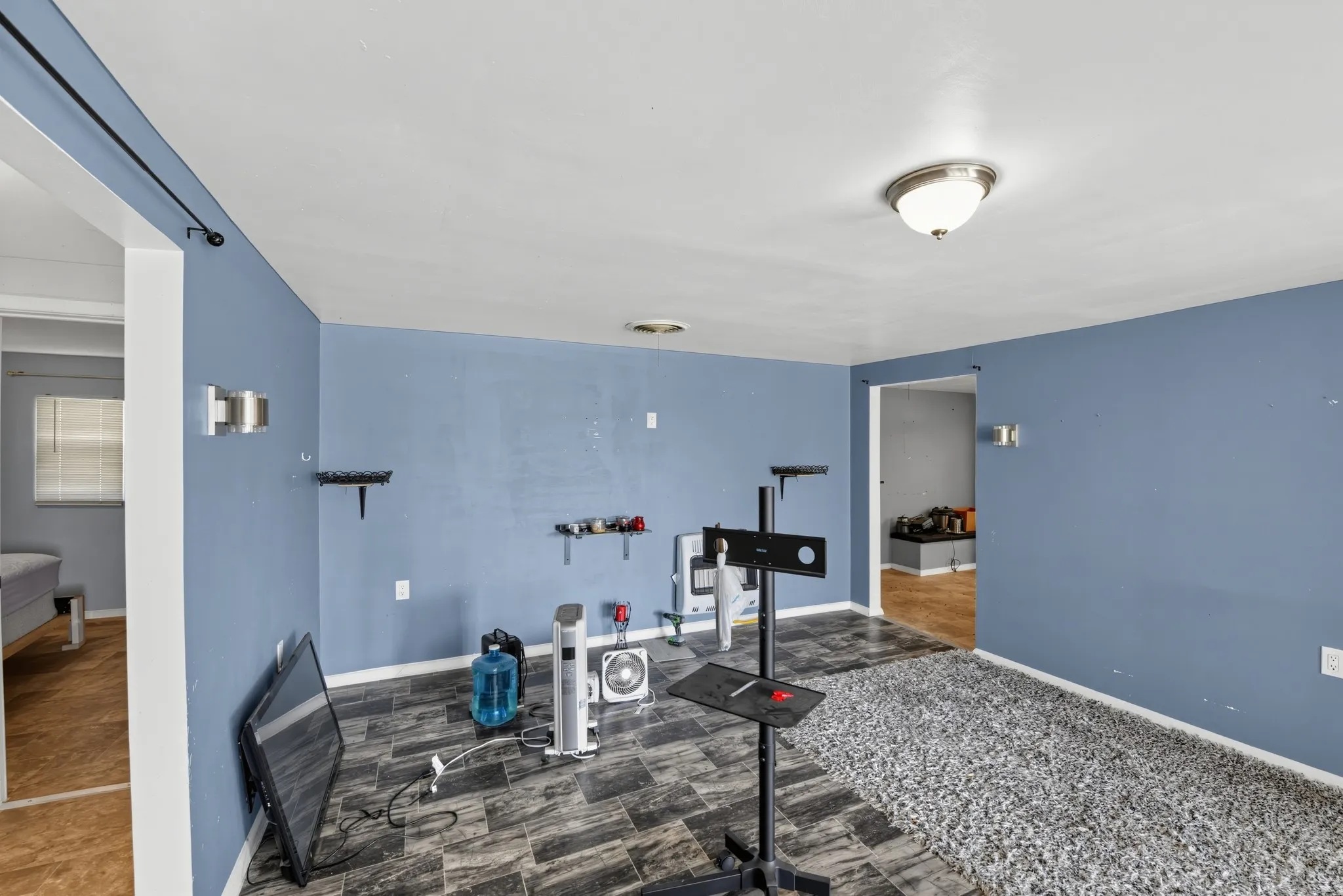 Room featuring a mixed flooring of tile and carpet, flush mount ceiling light, and wall sconces