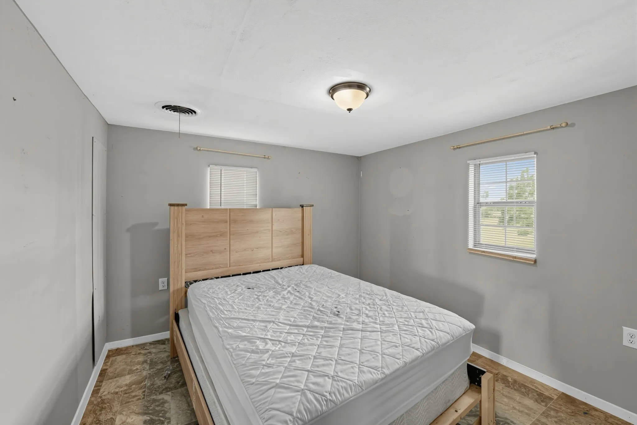 Recessed ceiling light fixture, window with blinds, and wood-finish flooring