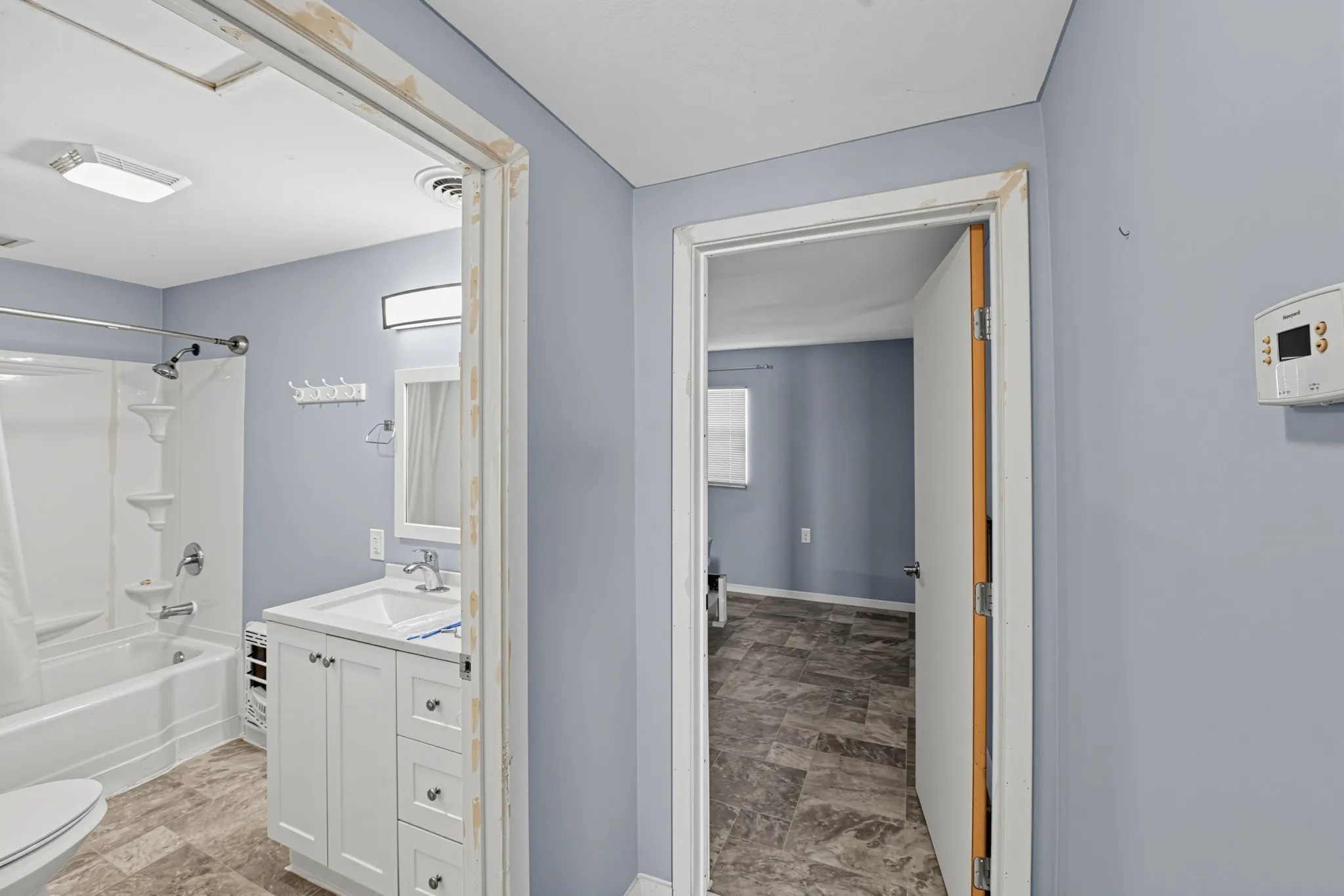 Bathroom featuring a white vanity with cabinet storage, a white rectangular sink, and a combination shower and tub
