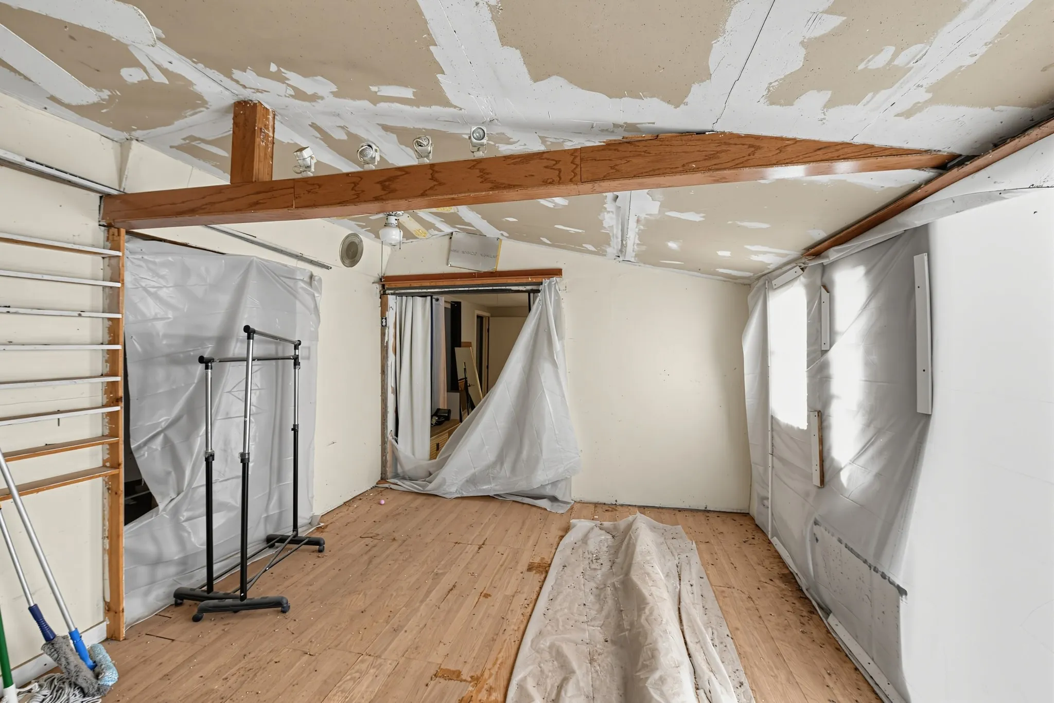 Exposed ceiling beam, wood-finish flooring, recessed lighting, and wall-mounted shelves
