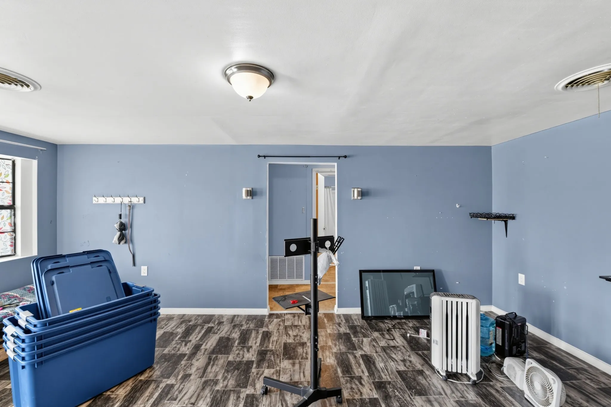 Wood-finish flooring, recessed ceiling lighting, wall-mounted sconces, and a large window