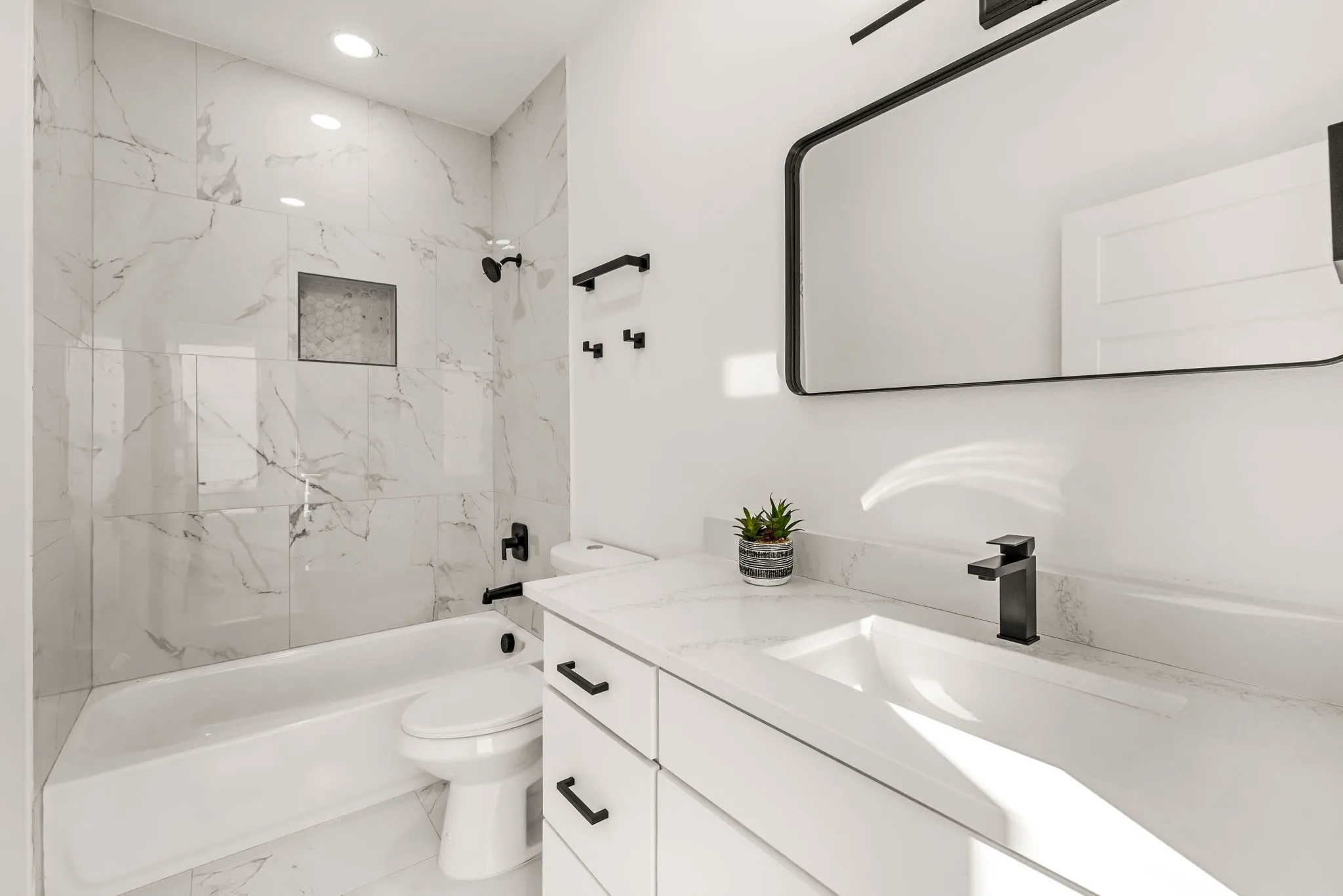 Bathroom featuring a white vanity with an integrated rectangular sink, matte black faucet, and white countertop