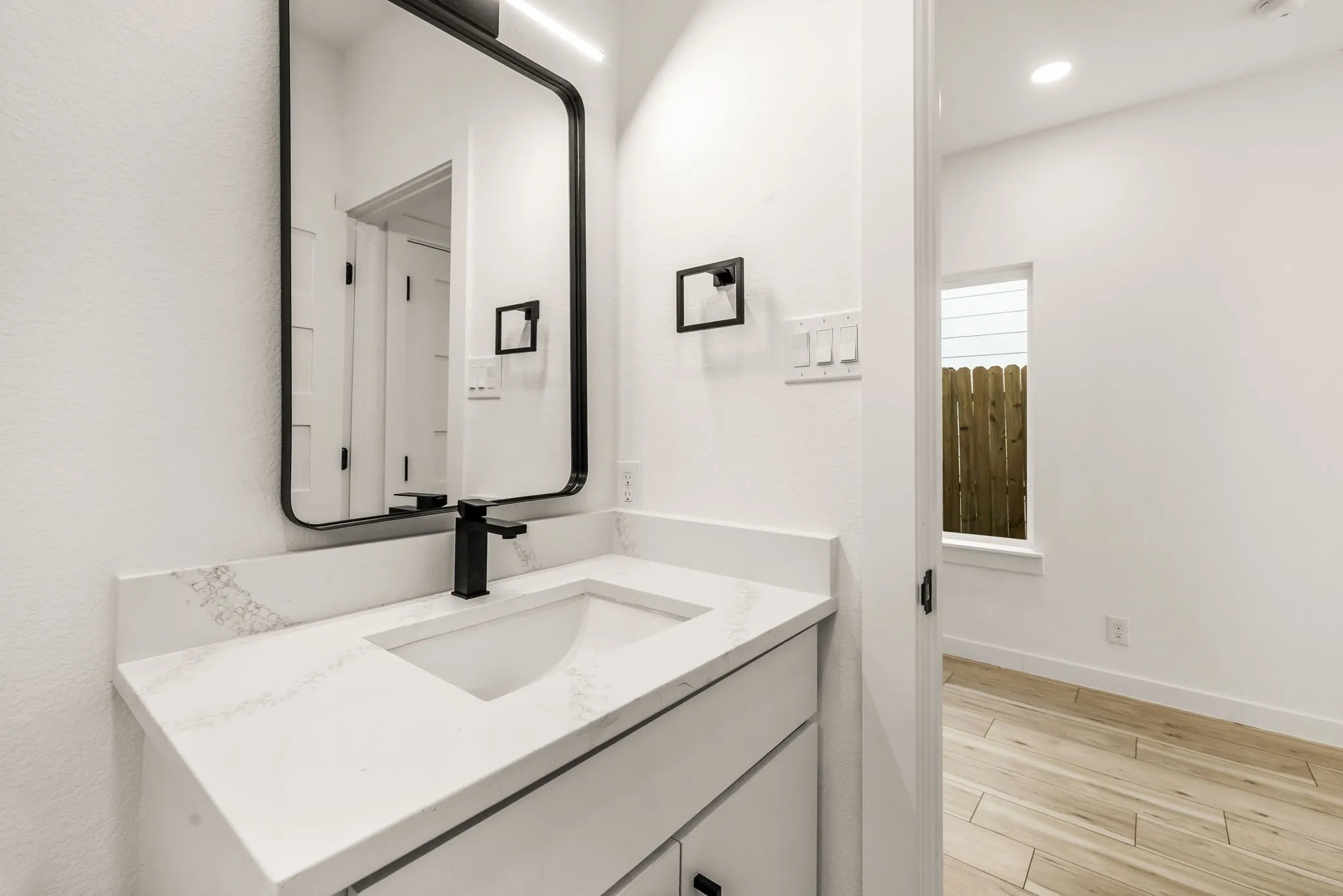 Vanity with a rectangular sink, matte black faucet, and white countertop