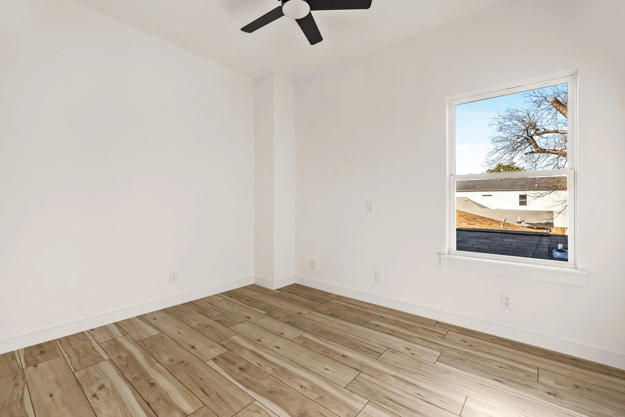 Wood-finish flooring, white painted walls, single window, and a ceiling fan