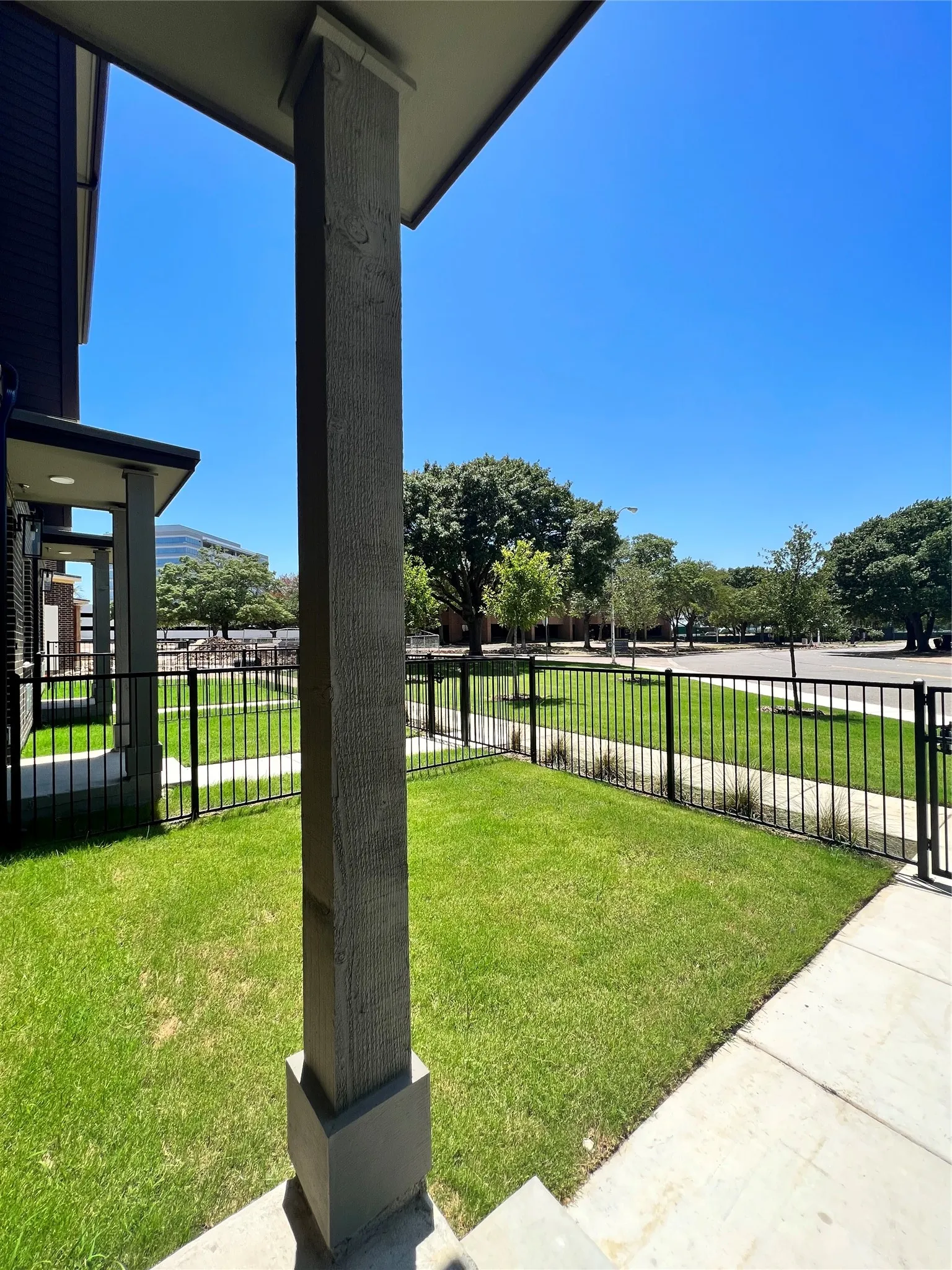 Landscaped front yard with a black metal fence and sidewalk access