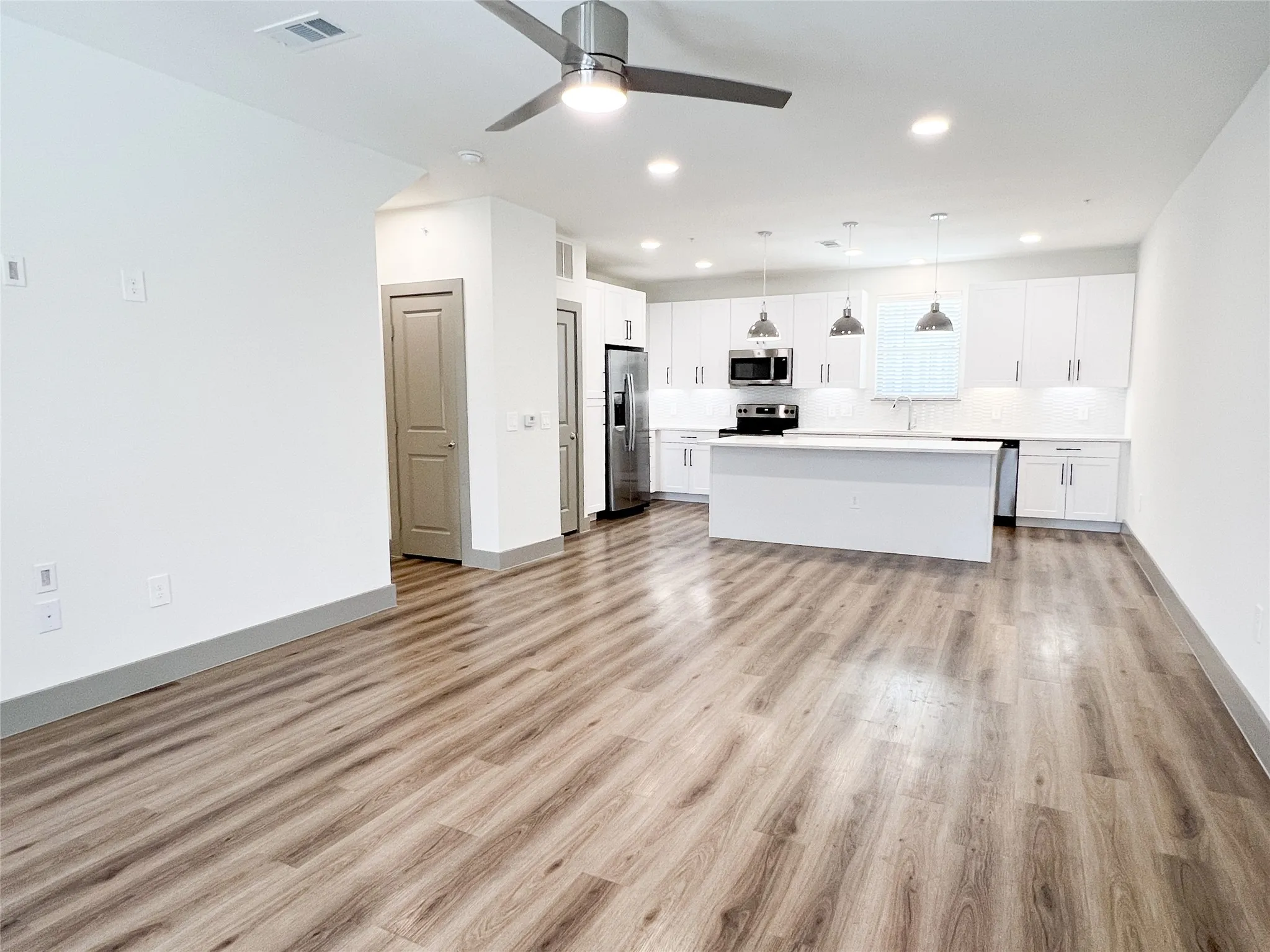 Kitchen with open floor plan, pendant lighting, a center island, white cabinets, and light countertops