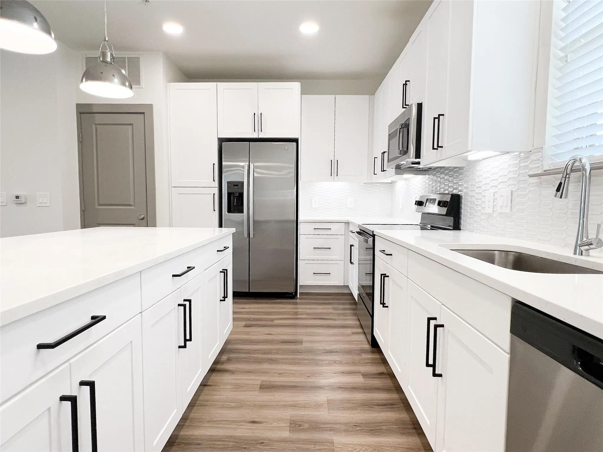 Kitchen featuring stainless steel appliances, white cabinetry, backsplash, light stone countertops, and light wood finished floors