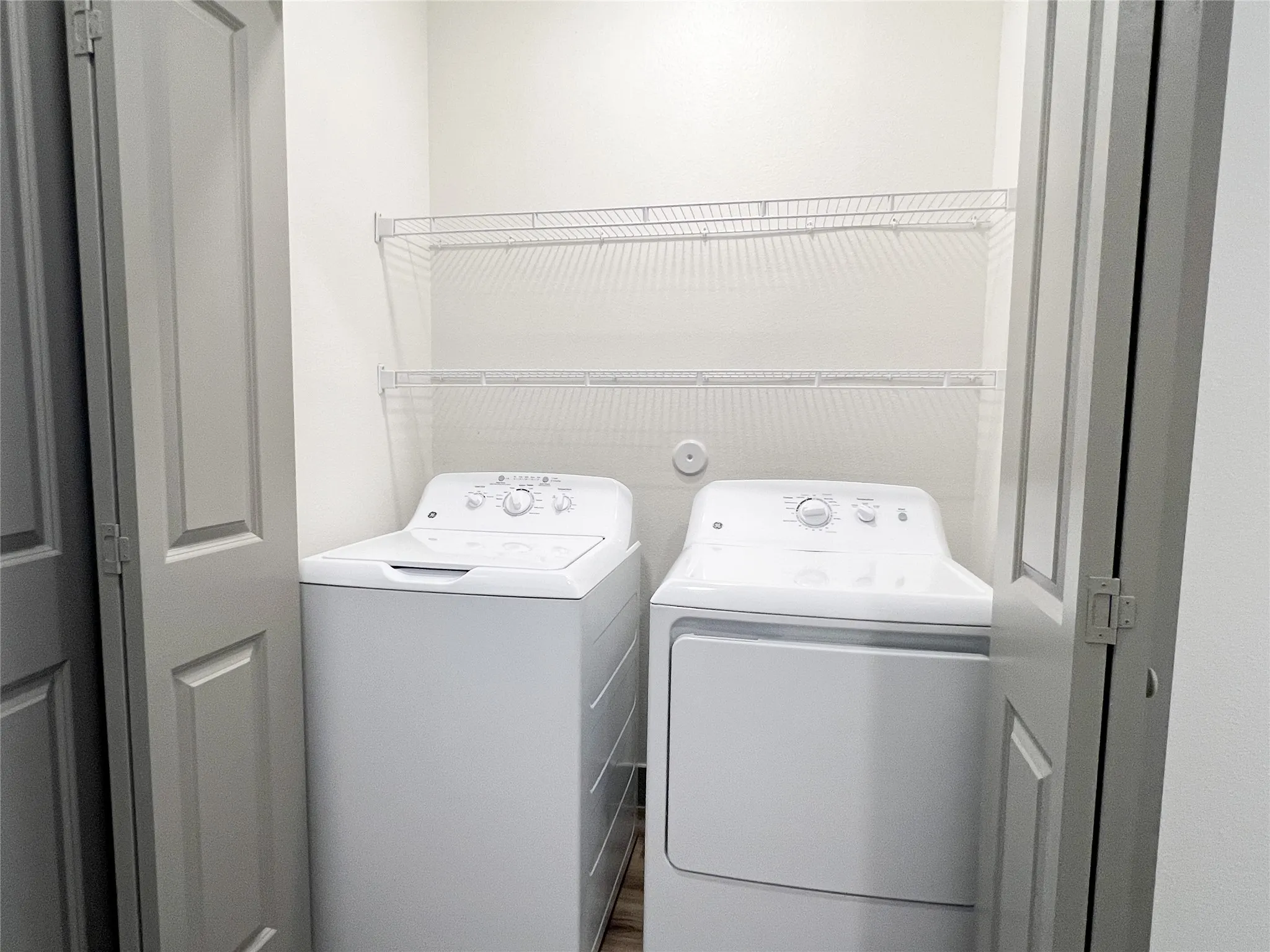 Laundry area with separate washer and dryer and wood finished floors