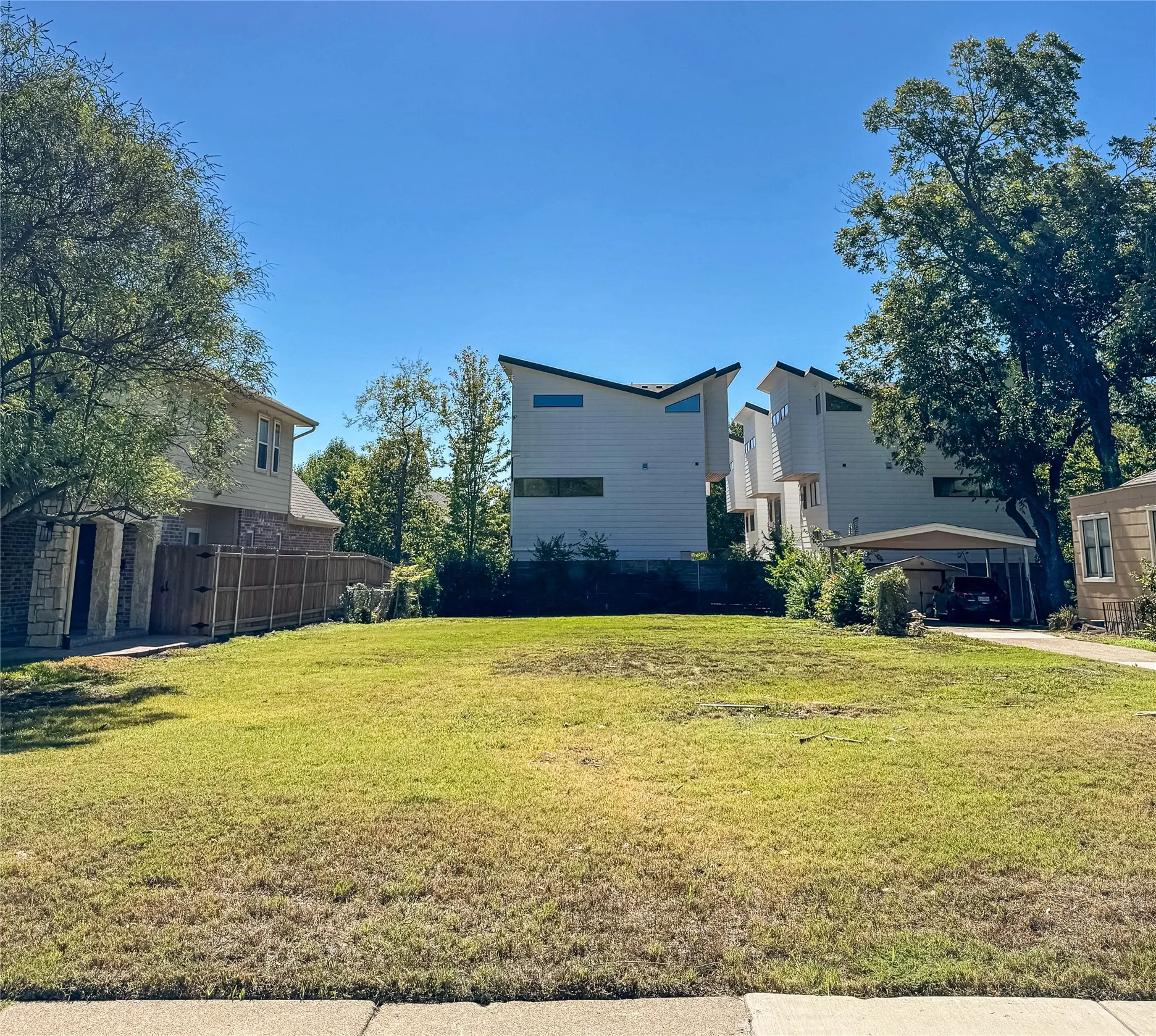 Expansive grassy lot with mature trees at the perimeter