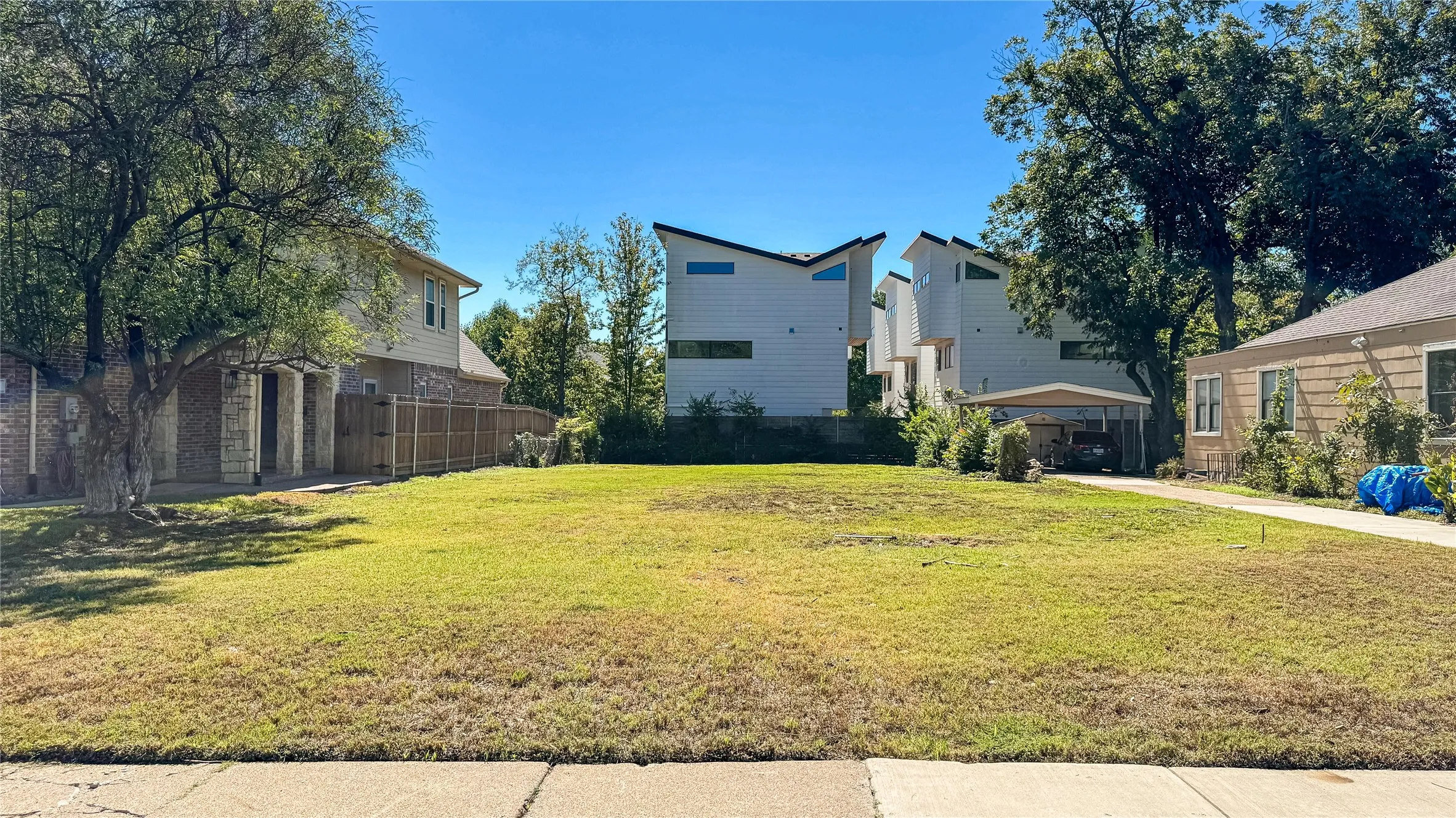 Expansive grassy lot with mature trees defining the perimeter