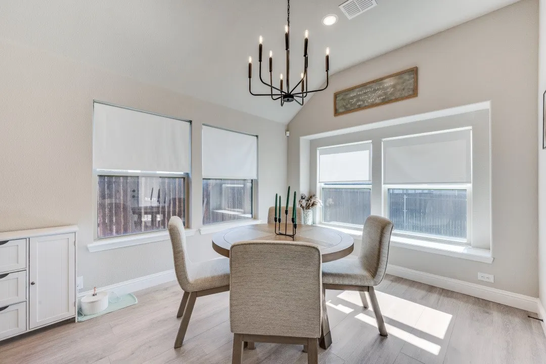 Vaulted ceiling, multiple windows, wood-finish flooring, recessed lighting, and a chandelier