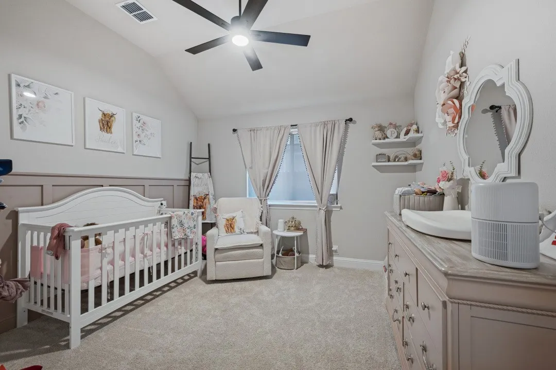 Vaulted ceiling with a ceiling fan, carpeted flooring, window with curtains, and a decorative wall panel accent