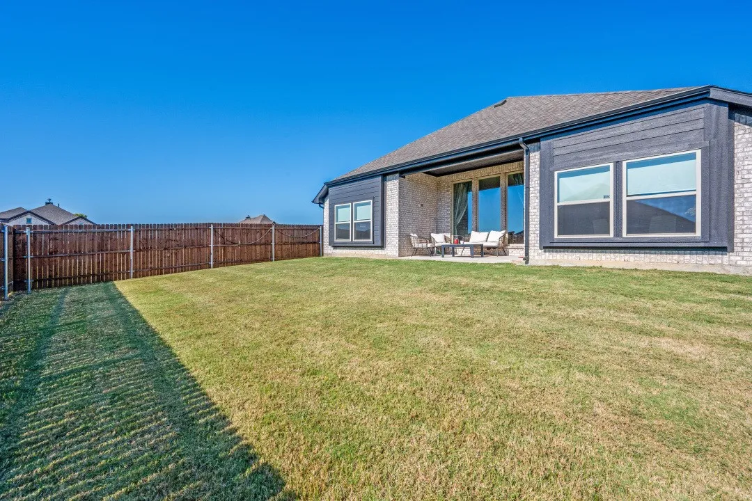 Expansive backyard featuring a privacy fence, covered patio, and large windows