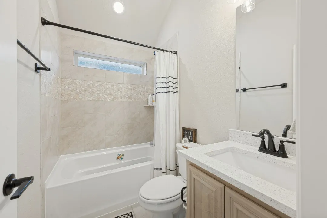 Tiled shower/tub combination with an accent mosaic band and transom window