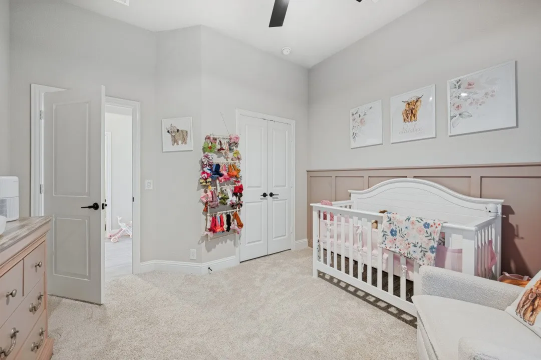 Neutral-toned walls with wainscoting detail, light-colored carpet, and a ceiling fan