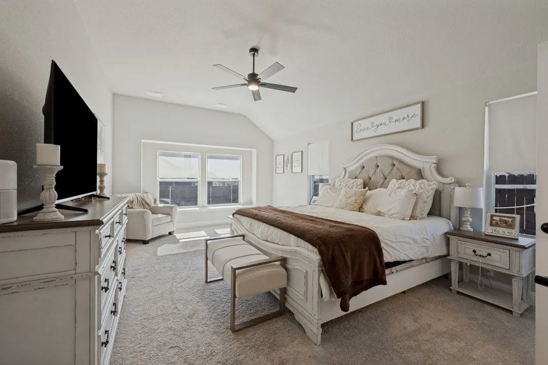 Vaulted ceiling, ceiling fan, carpet flooring, multiple windows, and a built-in window bench