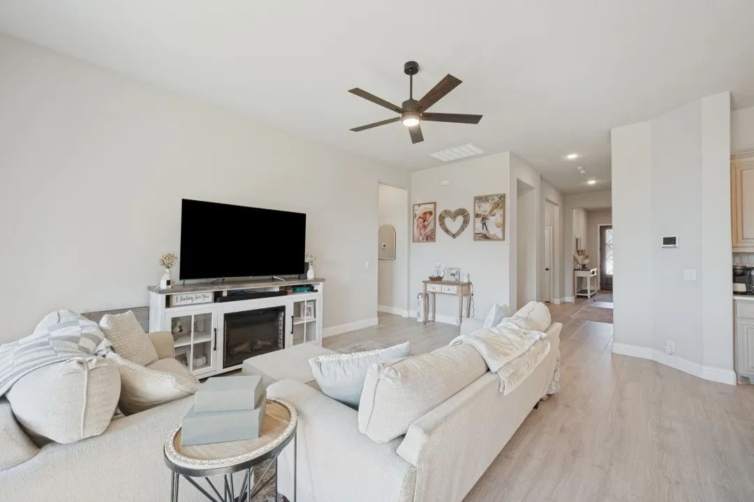 Recessed ceiling lighting, wood-finish flooring, ceiling fan with integrated lighting, built-in media console with electric fireplace, and neutral wall tones