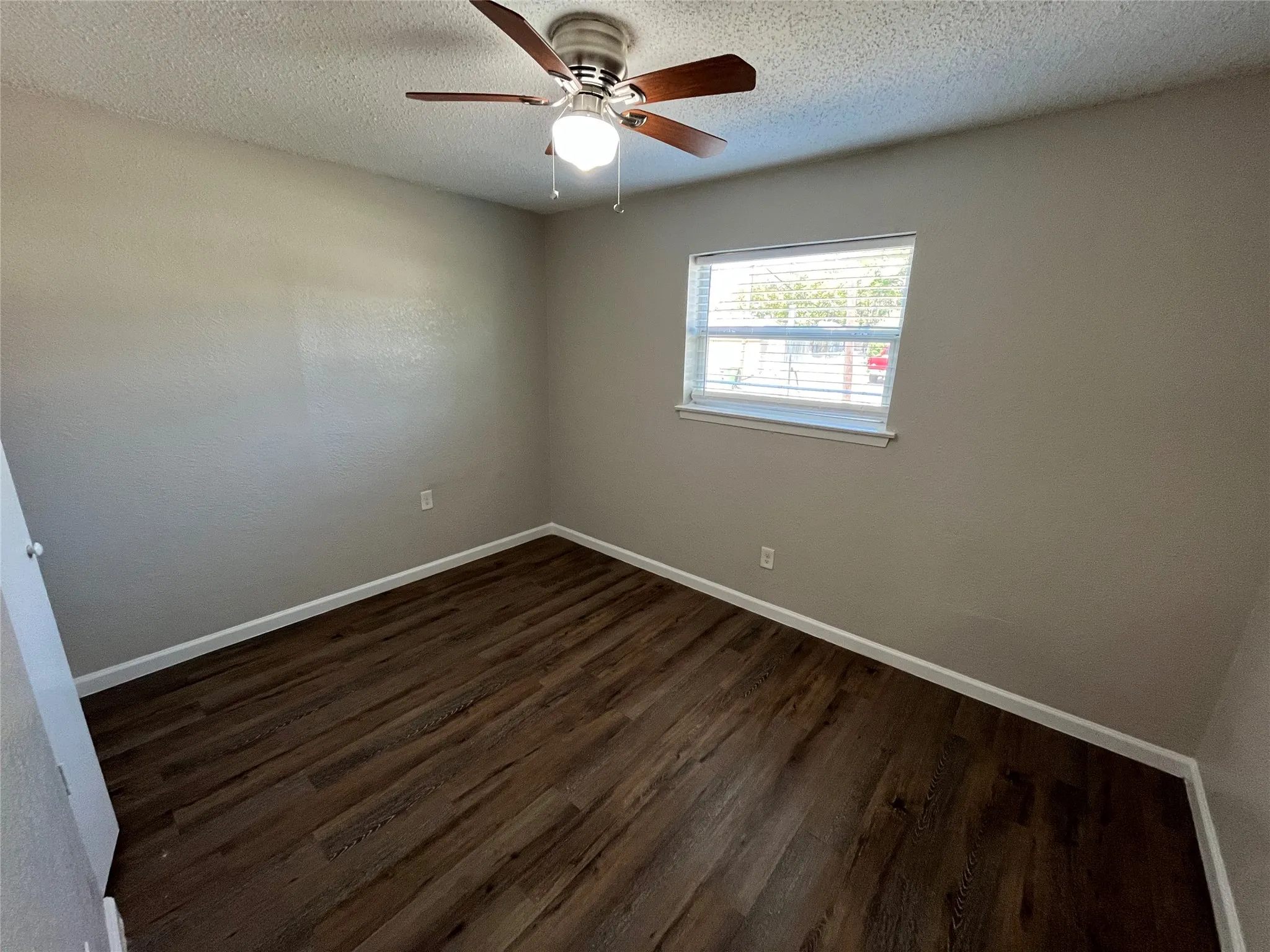 Wood-finish flooring, ceiling fan with integrated lighting, and a window with blinds