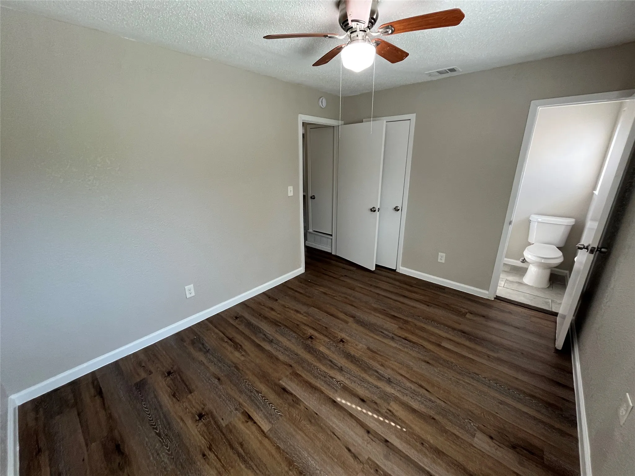 Wood-finish flooring throughout, ceiling fan with integrated lighting, and neutral wall tones